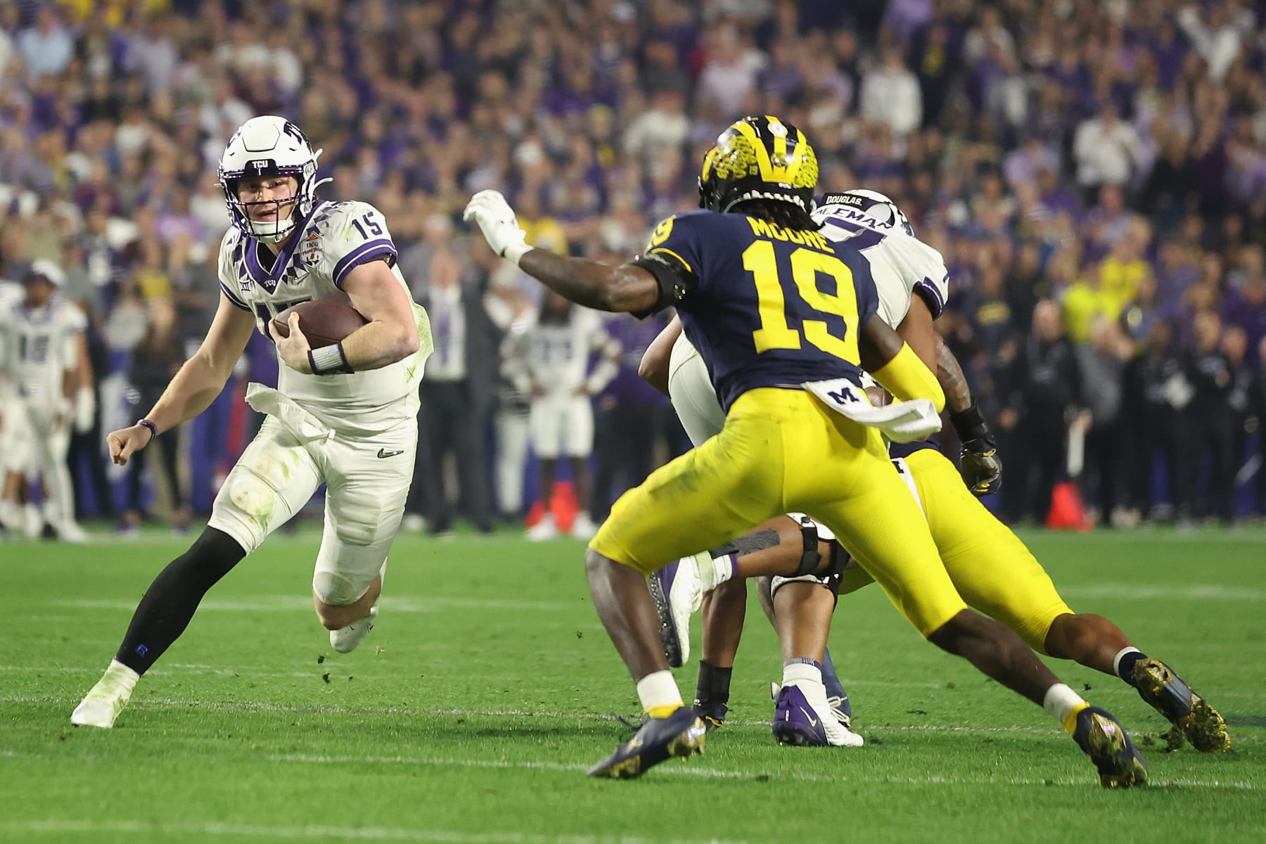 GLENDALE, ARIZONA - DECEMBER 31: Quarterback Max Duggan #15 of the TCU Horned Frogs scrambles with the football against Rod Moore #19 of the Michigan Wolverines during the fourth quarter of the Vrbo Fiesta Bowl at State Farm Stadium on December 31, 2022 in Glendale, Arizona. The Horned Frogs defeated the Wolverines 51-45.  (Photo by Christian Petersen/Getty Images)