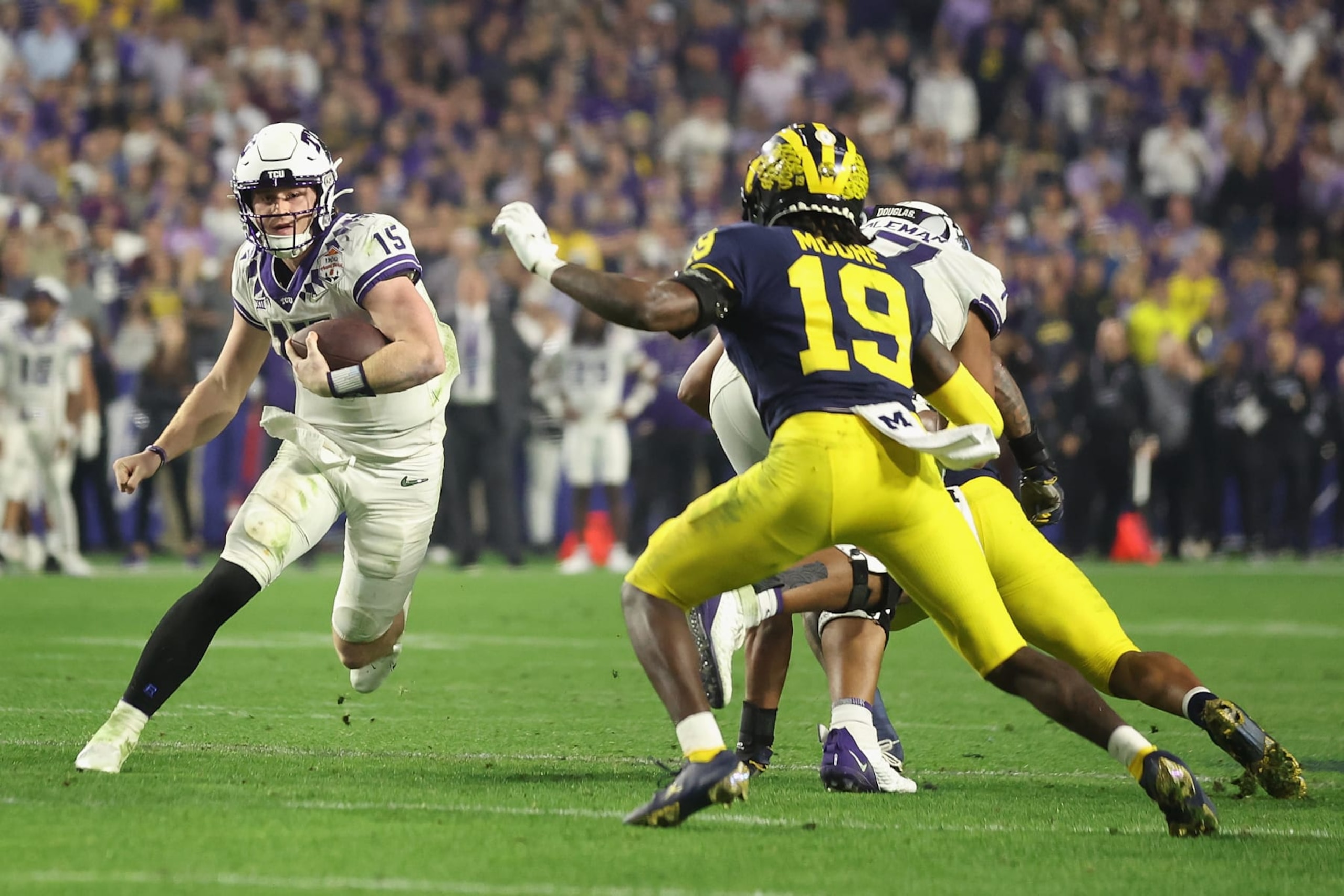 GLENDALE, ARIZONA - DECEMBER 31: Quarterback Max Duggan #15 of the TCU Horned Frogs scrambles with the football against Rod Moore #19 of the Michigan Wolverines during the fourth quarter of the Vrbo Fiesta Bowl at State Farm Stadium on December 31, 2022 in Glendale, Arizona. The Horned Frogs defeated the Wolverines 51-45.  (Photo by Christian Petersen/Getty Images)