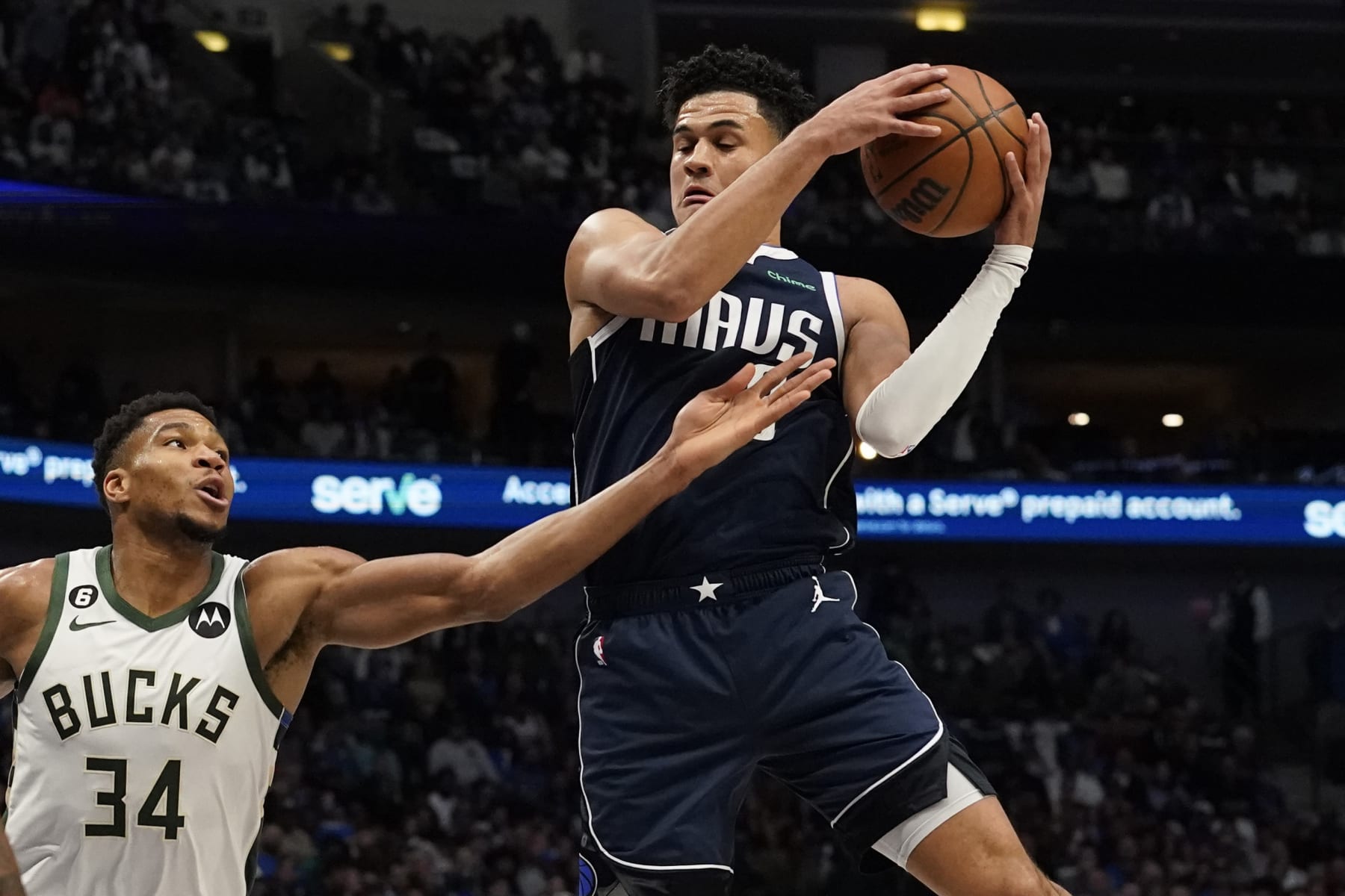 Dallas Mavericks guard Tyler Dorsey, right, grabs a rebound against Milwaukee Bucks forward Giannis Antetokounmpo (34) during the first half of an NBA basketball game in Dallas, Friday, Dec. 9, 2022. (AP Photo/LM Otero)