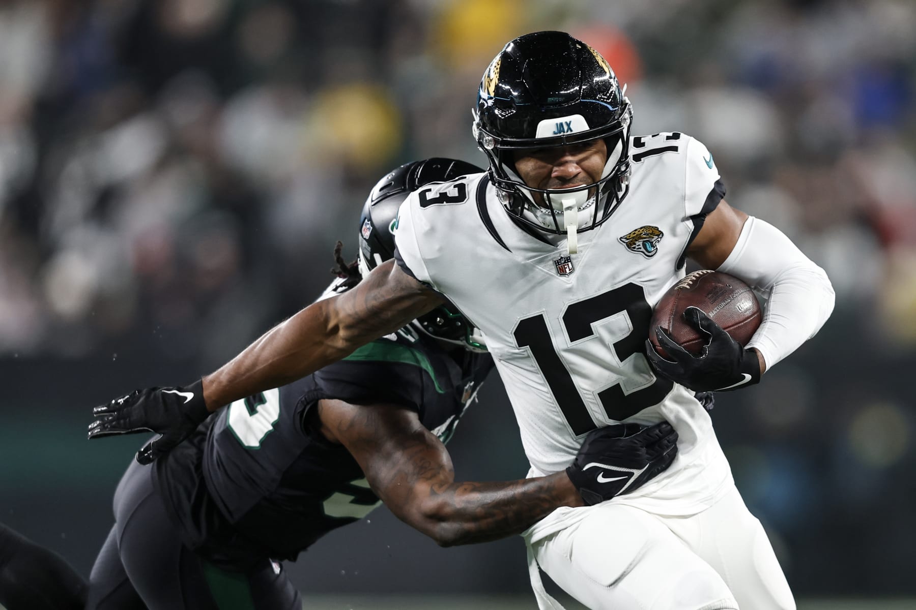 EAST RUTHERFORD, NEW JERSEY - DECEMBER 22: Christian Kirk #13 of the Jacksonville Jaguars runs with the ball against Quincy Williams #56 of the New York Jets during an NFL football game between the New York Jets and the Jacksonville Jaguars at MetLife Stadium on December 22, 2022 in East Rutherford, New Jersey. (Photo by Michael Owens/Getty Images)
