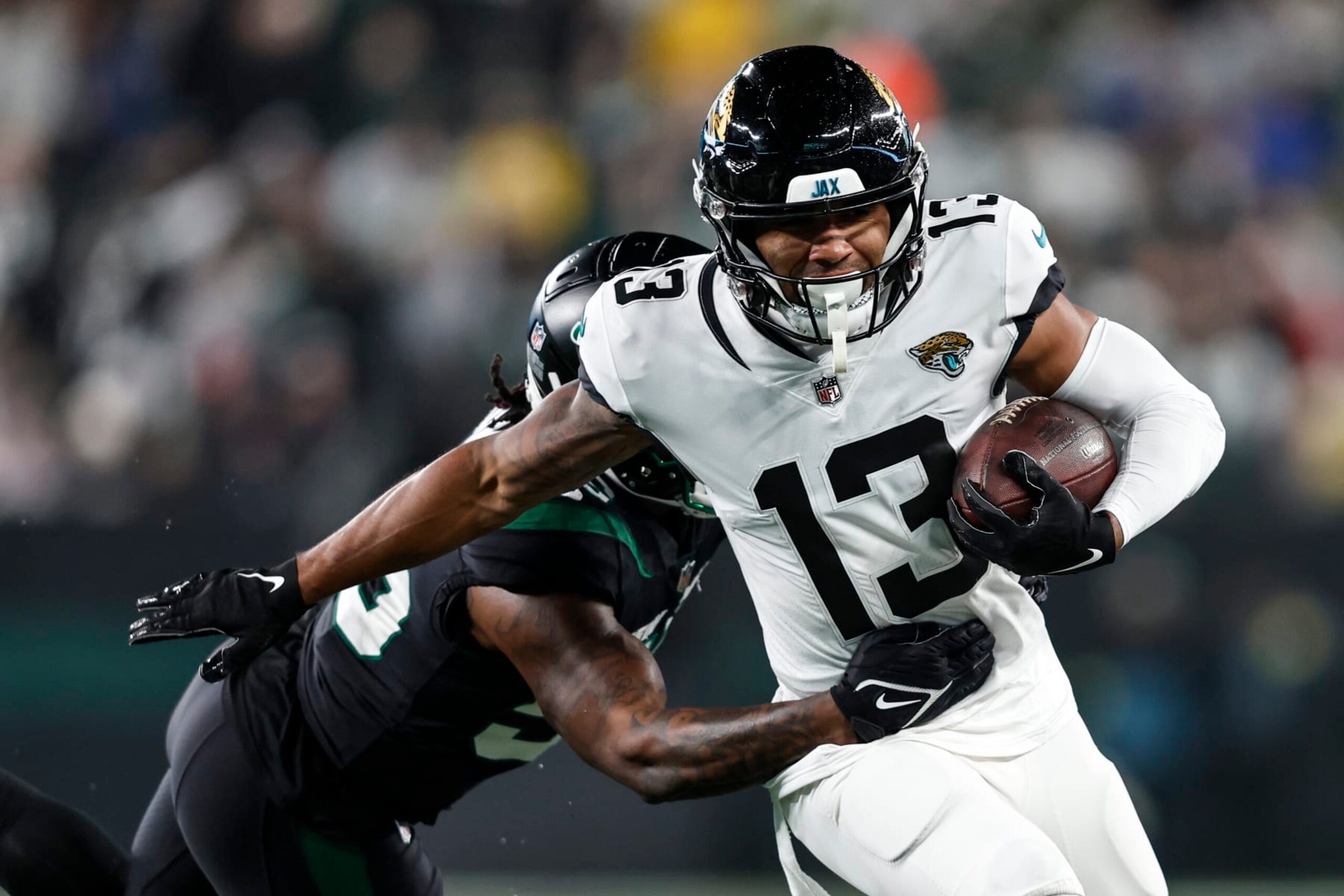 EAST RUTHERFORD, NEW JERSEY - DECEMBER 22: Christian Kirk #13 of the Jacksonville Jaguars runs with the ball against Quincy Williams #56 of the New York Jets during an NFL football game between the New York Jets and the Jacksonville Jaguars at MetLife Stadium on December 22, 2022 in East Rutherford, New Jersey. (Photo by Michael Owens/Getty Images)