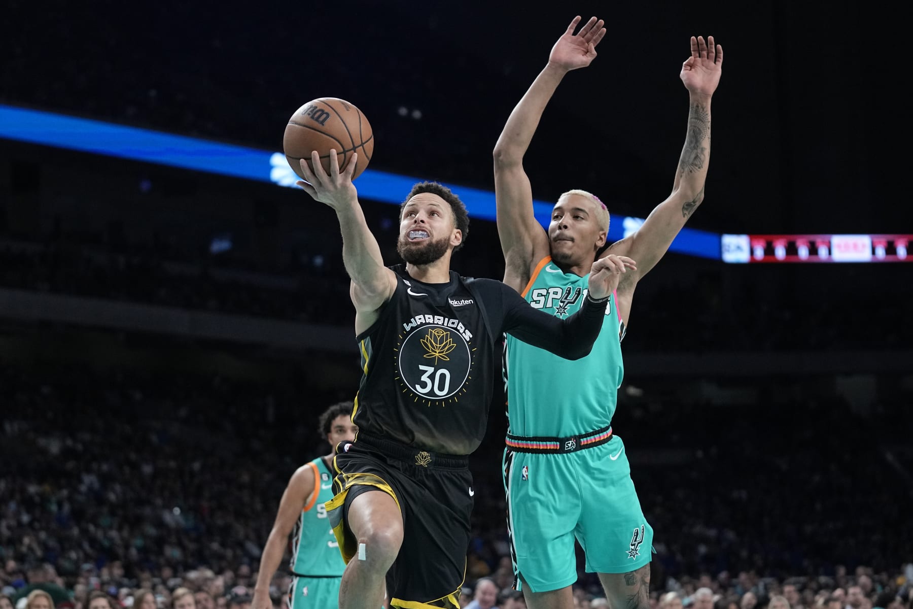 Golden State Warriors guard Stephen Curry (30) drives to the basket past San Antonio Spurs forward Jeremy Sochan, right, during the first half of an NBA basketball game in San Antonio, Friday, Jan. 13, 2023. (AP Photo/Eric Gay)