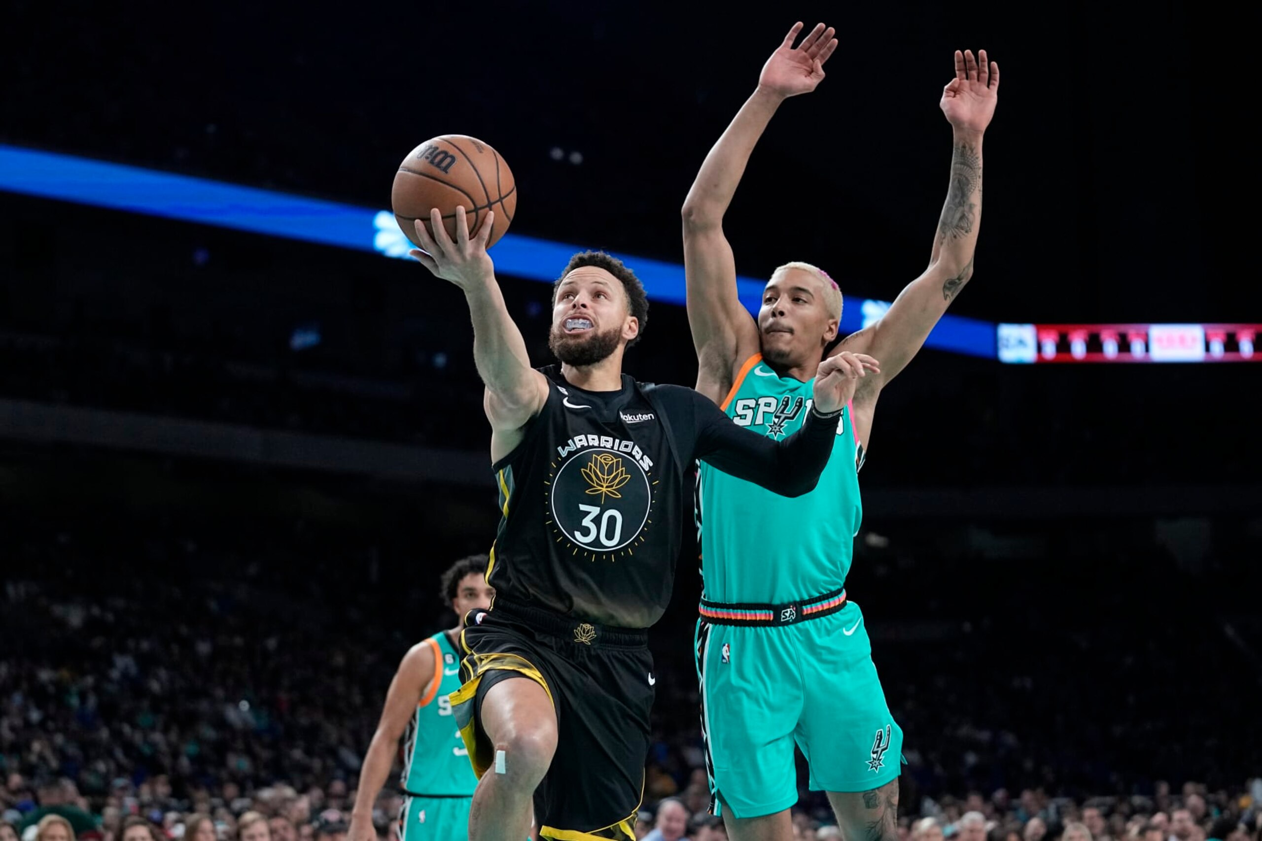 Golden State Warriors guard Stephen Curry (30) drives to the basket past San Antonio Spurs forward Jeremy Sochan, right, during the first half of an NBA basketball game in San Antonio, Friday, Jan. 13, 2023. (AP Photo/Eric Gay)