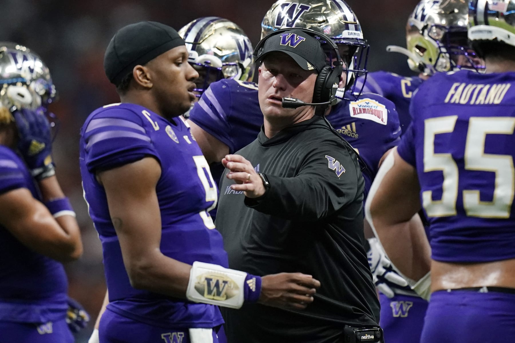 Washington head coach Kalen DeBoer, center, talks with quarterback Michael Penix Jr. (9) during the first half of the Alamo Bowl NCAA college football game against Texas in San Antonio, Thursday, Dec. 29, 2022. (AP Photo/Eric Gay)