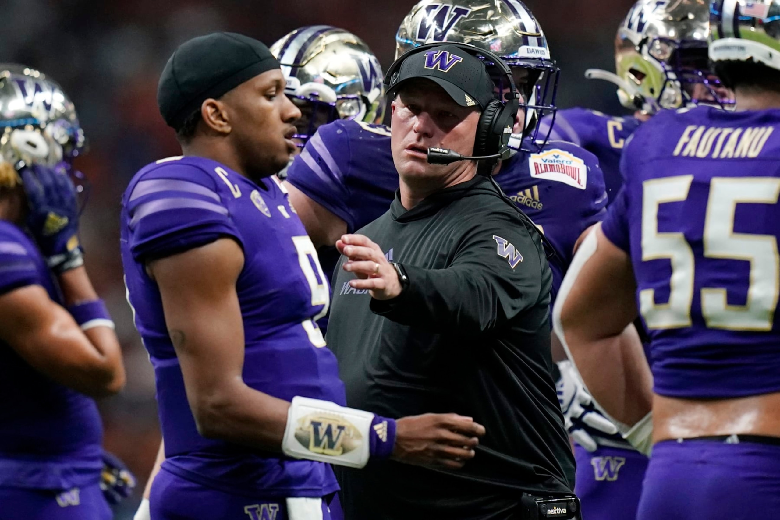 Washington head coach Kalen DeBoer, center, talks with quarterback Michael Penix Jr. (9) during the first half of the Alamo Bowl NCAA college football game against Texas in San Antonio, Thursday, Dec. 29, 2022. (AP Photo/Eric Gay)