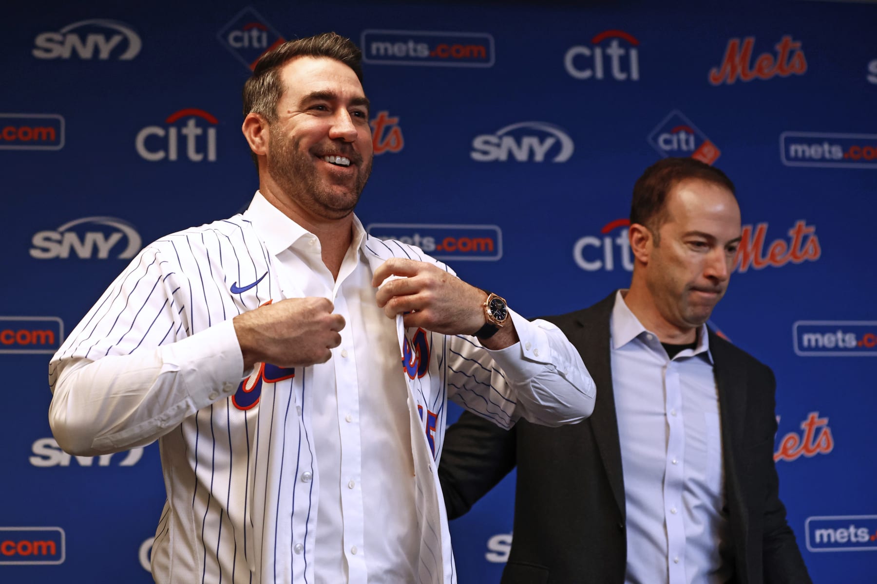 NEW YORK, NY - DECEMBER 20: Pitcher Justin Verlander of the New York Mets puts on his new jersey as he stands beside general manager Billy Eppler before he is introduced during a press conference at Citi Field on December 20, 2022 in New York City. (Photo by Rich Schultz/Getty Images)