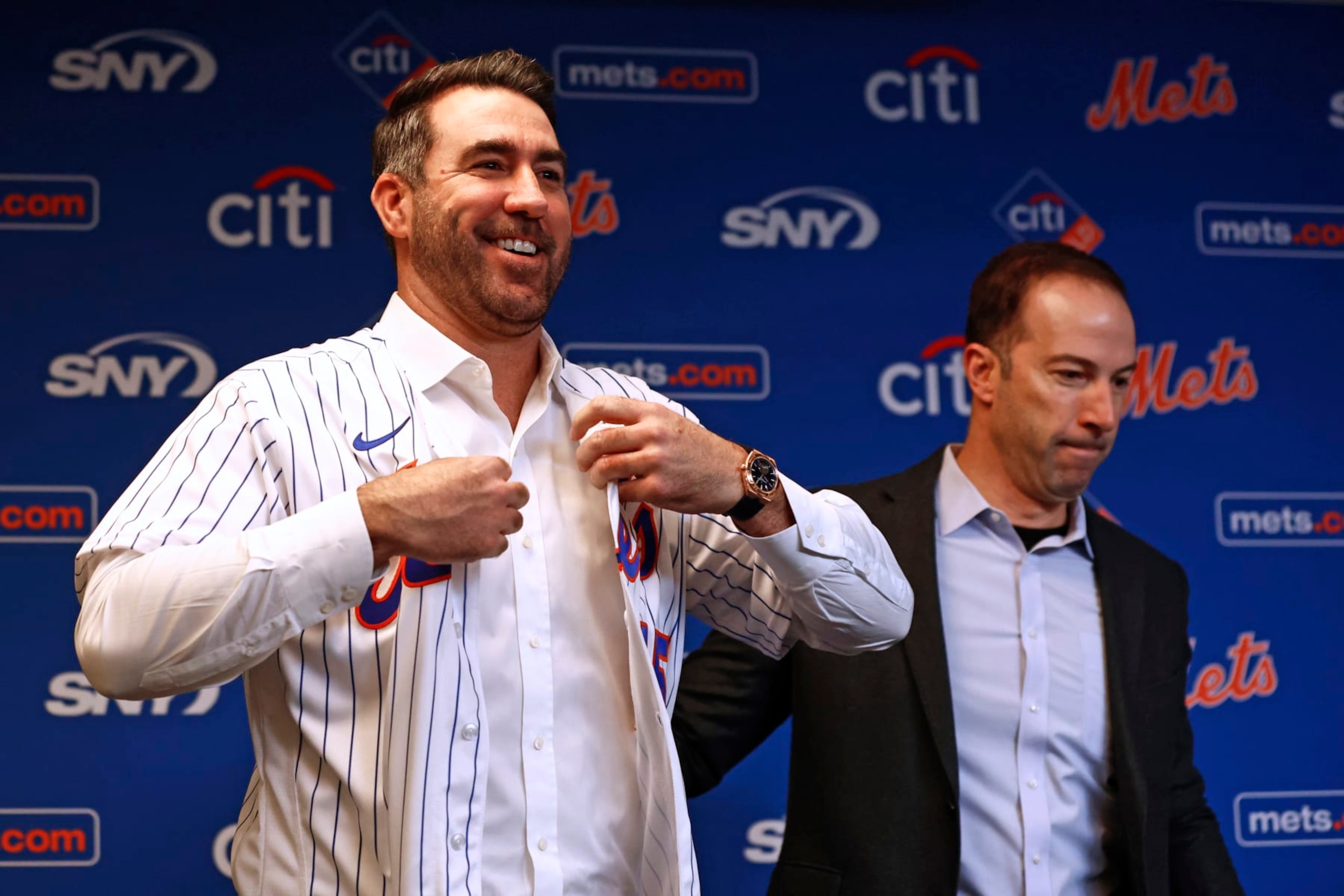 NEW YORK, NY - DECEMBER 20: Pitcher Justin Verlander of the New York Mets puts on his new jersey as he stands beside general manager Billy Eppler before he is introduced during a press conference at Citi Field on December 20, 2022 in New York City. (Photo by Rich Schultz/Getty Images)
