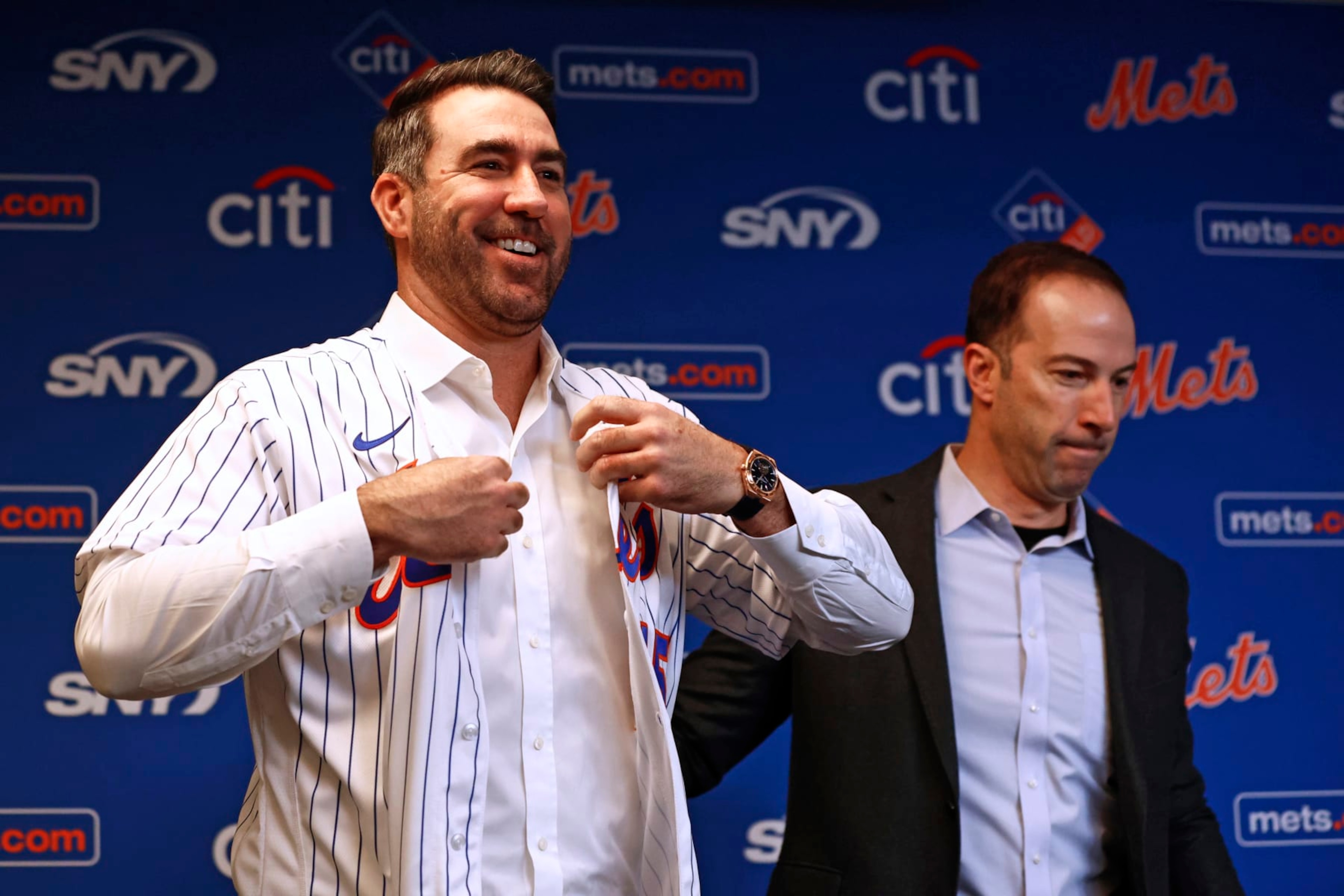 NEW YORK, NY - DECEMBER 20: Pitcher Justin Verlander of the New York Mets puts on his new jersey as he stands beside general manager Billy Eppler before he is introduced during a press conference at Citi Field on December 20, 2022 in New York City. (Photo by Rich Schultz/Getty Images)