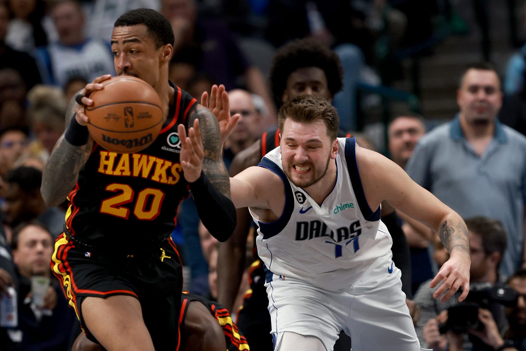 DALLAS, TEXAS - JANUARY 18: John Collins #20 of the Atlanta Hawks scrambles for the ball against Luka Doncic #77 of the Dallas Mavericks in the second quarter at American Airlines Center on January 18, 2023 in Dallas, Texas. NOTE TO USER: User expressly acknowledges and agrees that, by downloading and or using this photograph, User is consenting to the terms and conditions of the Getty Images License Agreement. (Photo by Tom Pennington/Getty Images)