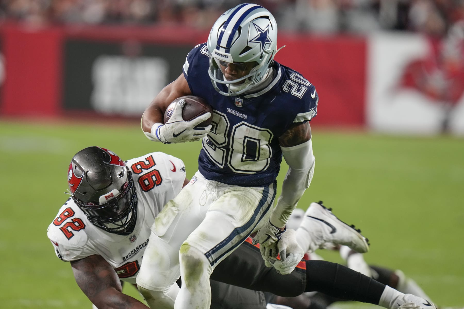 Dallas Cowboys running back Tony Pollard (20) runs near Tampa Bay Buccaneers defensive end William Gholston (92) during the second half of an NFL wild-card football game, Monday, Jan. 16, 2023, in Tampa, Fla. (AP Photo/Chris O'Meara)