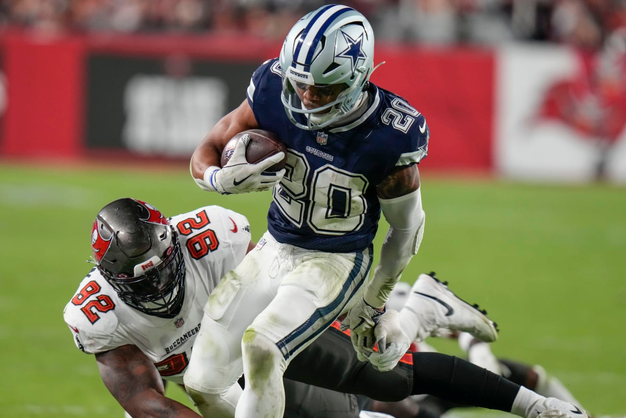 Dallas Cowboys running back Tony Pollard (20) runs near Tampa Bay Buccaneers defensive end William Gholston (92) during the second half of an NFL wild-card football game, Monday, Jan. 16, 2023, in Tampa, Fla. (AP Photo/Chris O'Meara)