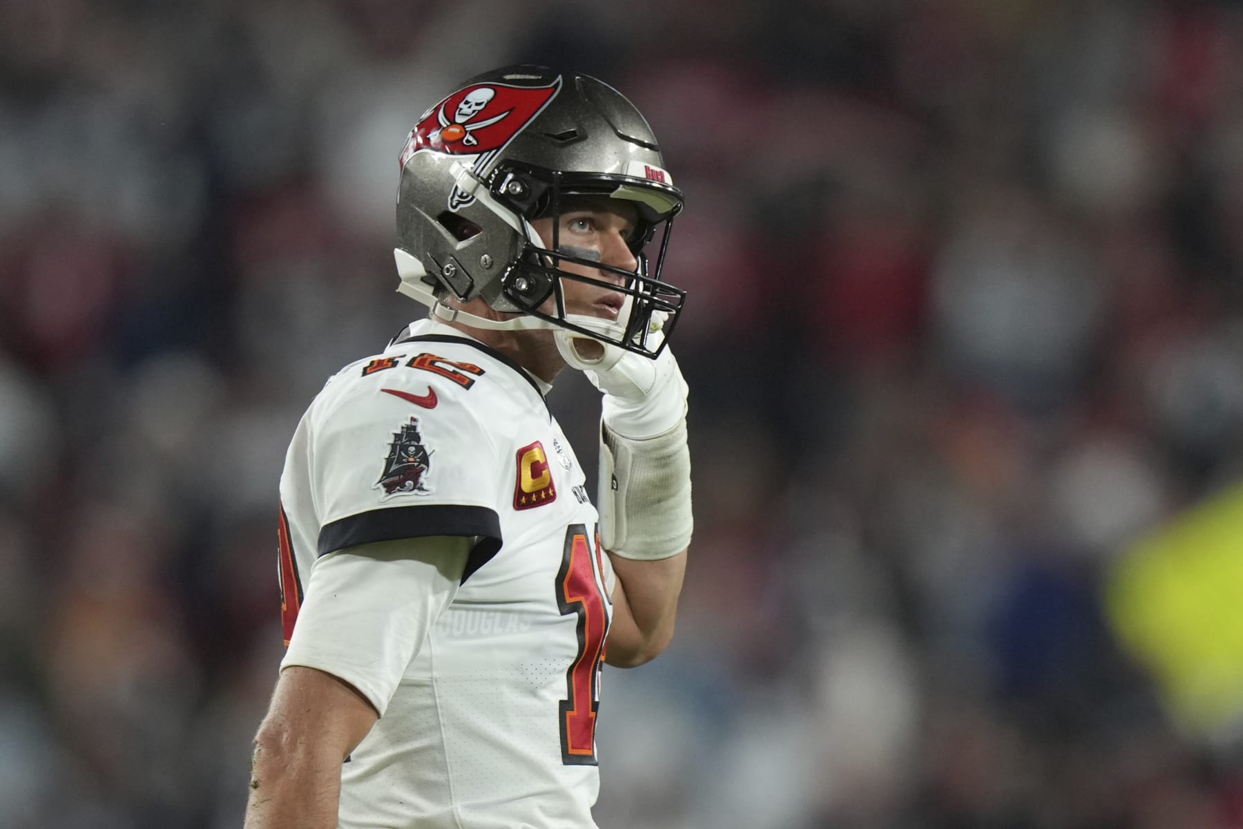 Tampa Bay Buccaneers quarterback Tom Brady (12) shows his frustration as he removes his chin strap while walking to the team bench during an NFL wild-card football game against the ,Dallas Cowboys Monday, Jan. 16, 2023, in Tampa, Fla. (AP Photo/Peter Joneleit)