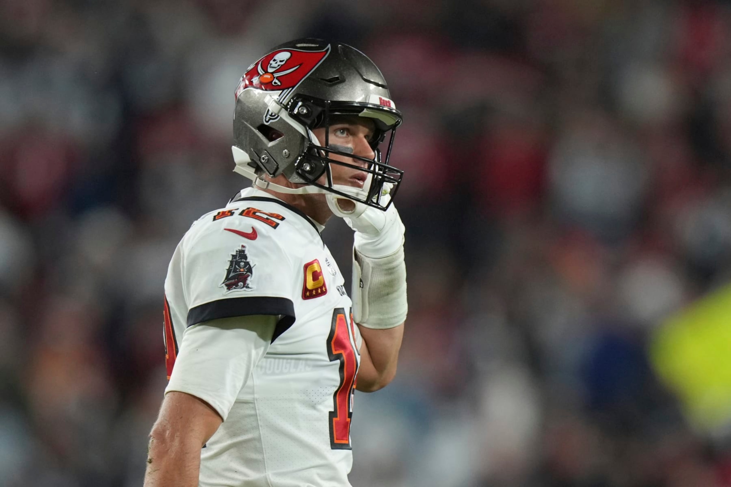 Tampa Bay Buccaneers quarterback Tom Brady (12) shows his frustration as he removes his chin strap while walking to the team bench during an NFL wild-card football game against the ,Dallas Cowboys Monday, Jan. 16, 2023, in Tampa, Fla. (AP Photo/Peter Joneleit)