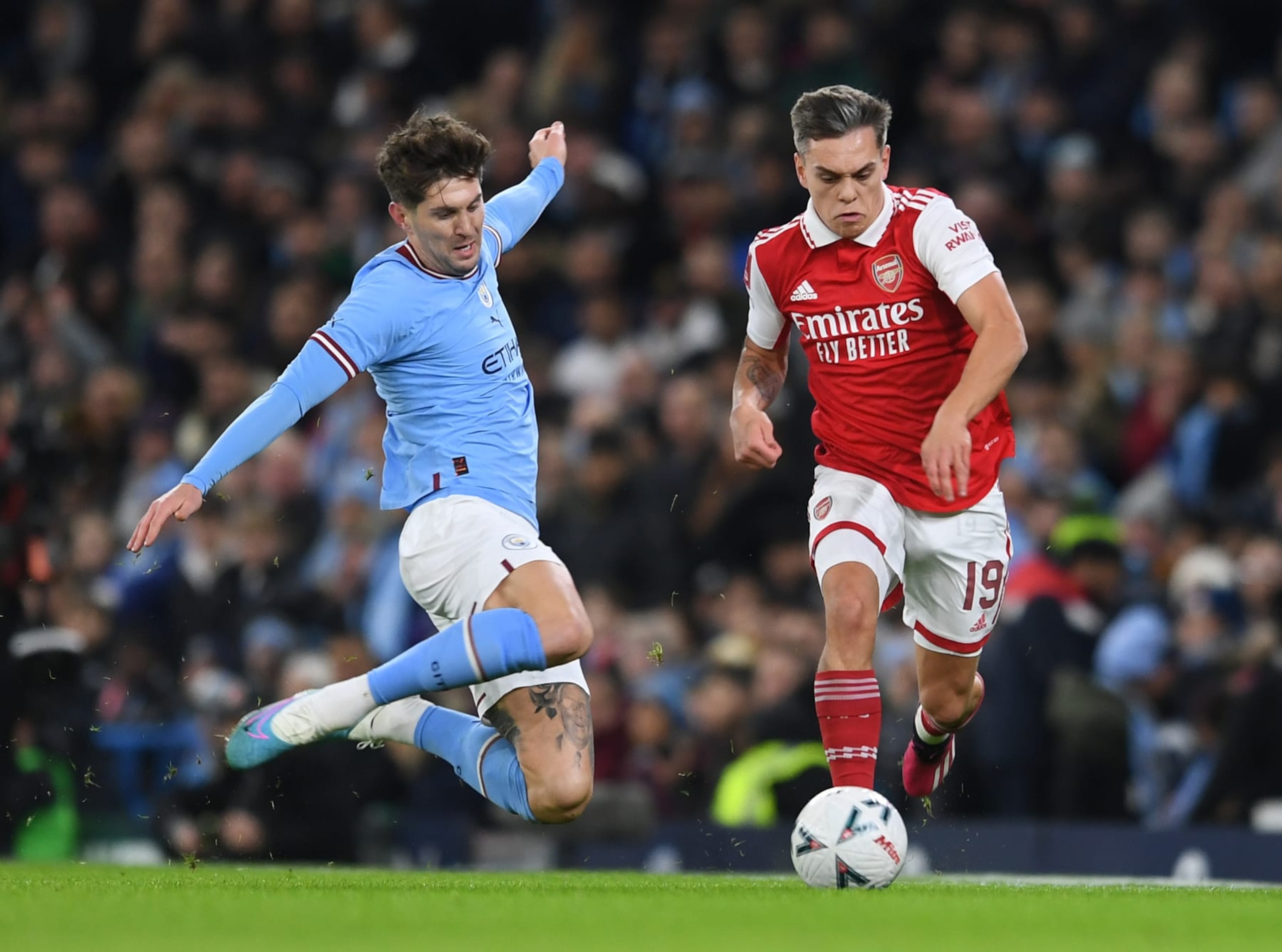 MANCHESTER, ENGLAND - JANUARY 27: Leandro Trossard of Arsenal is challenged by John Stones of Man City during the FA Cup 4th round match between Manchester City and Arsenal at Etihad Stadium on January 27, 2023 in Manchester, England. (Photo by David Price/Arsenal FC via Getty Images)