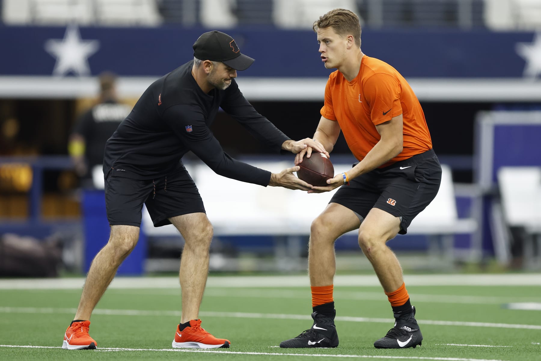 ARLINGTON, TEXAS - SEPTEMBER 18: Joe Burrow #9 of the Cincinnati Bengals runs warmup drills with quarterbacks coach Dan Pitcher before the game against the Dallas Cowboys at AT&T Stadium on September 18, 2022 in Arlington, Texas. (Photo by Wesley Hitt/Getty Images)