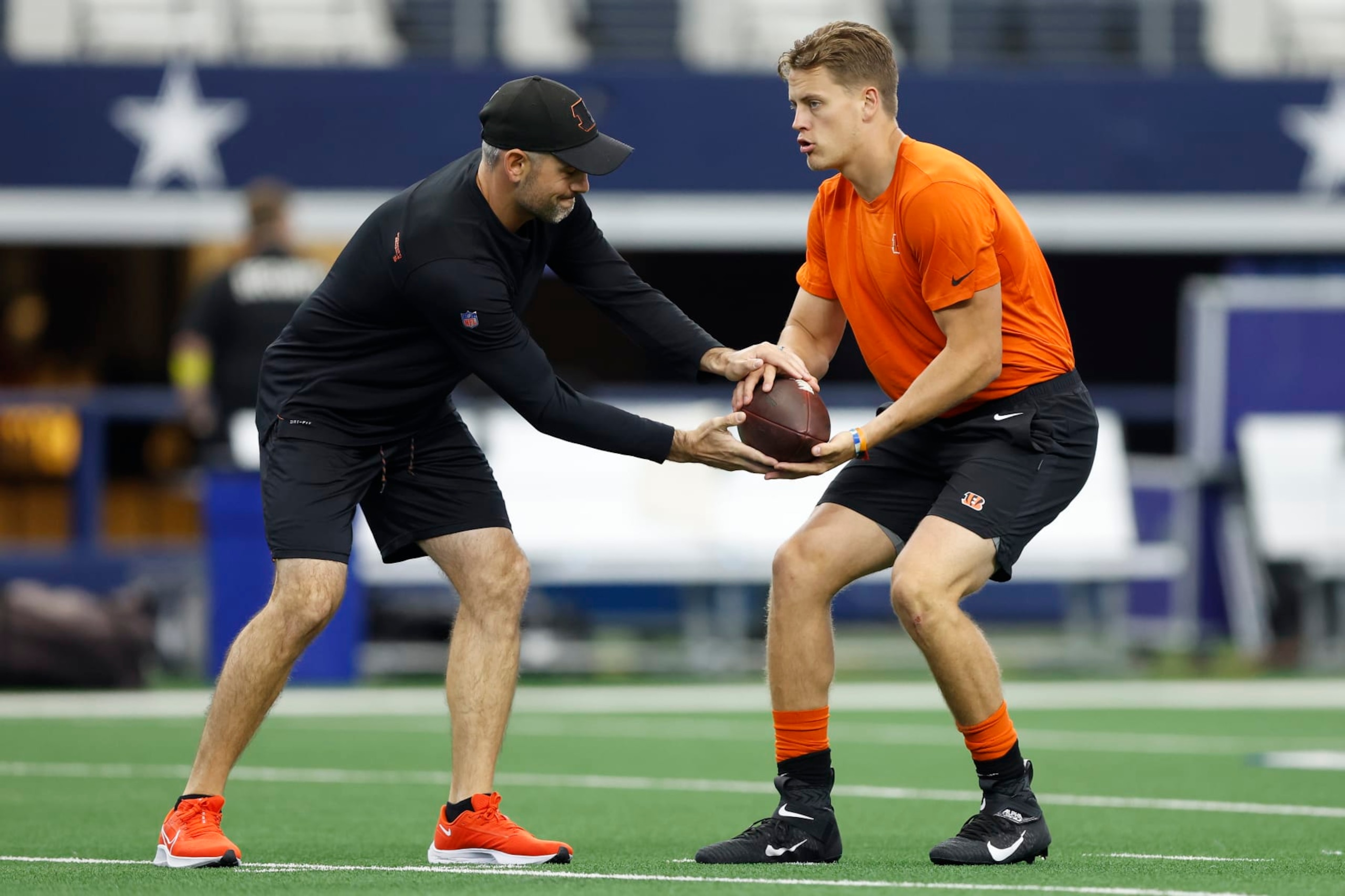 ARLINGTON, TEXAS - SEPTEMBER 18: Joe Burrow #9 of the Cincinnati Bengals runs warmup drills with quarterbacks coach Dan Pitcher before the game against the Dallas Cowboys at AT&T Stadium on September 18, 2022 in Arlington, Texas. (Photo by Wesley Hitt/Getty Images) ARLINGTON, TEXAS - SEPTEMBER 18: Joe Burrow #9 of the Cincinnati Bengals runs warmup drills with quarterbacks coach Dan Pitcher before the game against the Dallas Cowboys at AT&T Stadium on September 18, 2022 in Arlington, Texas. (Photo by Wesley Hitt/Getty Images)