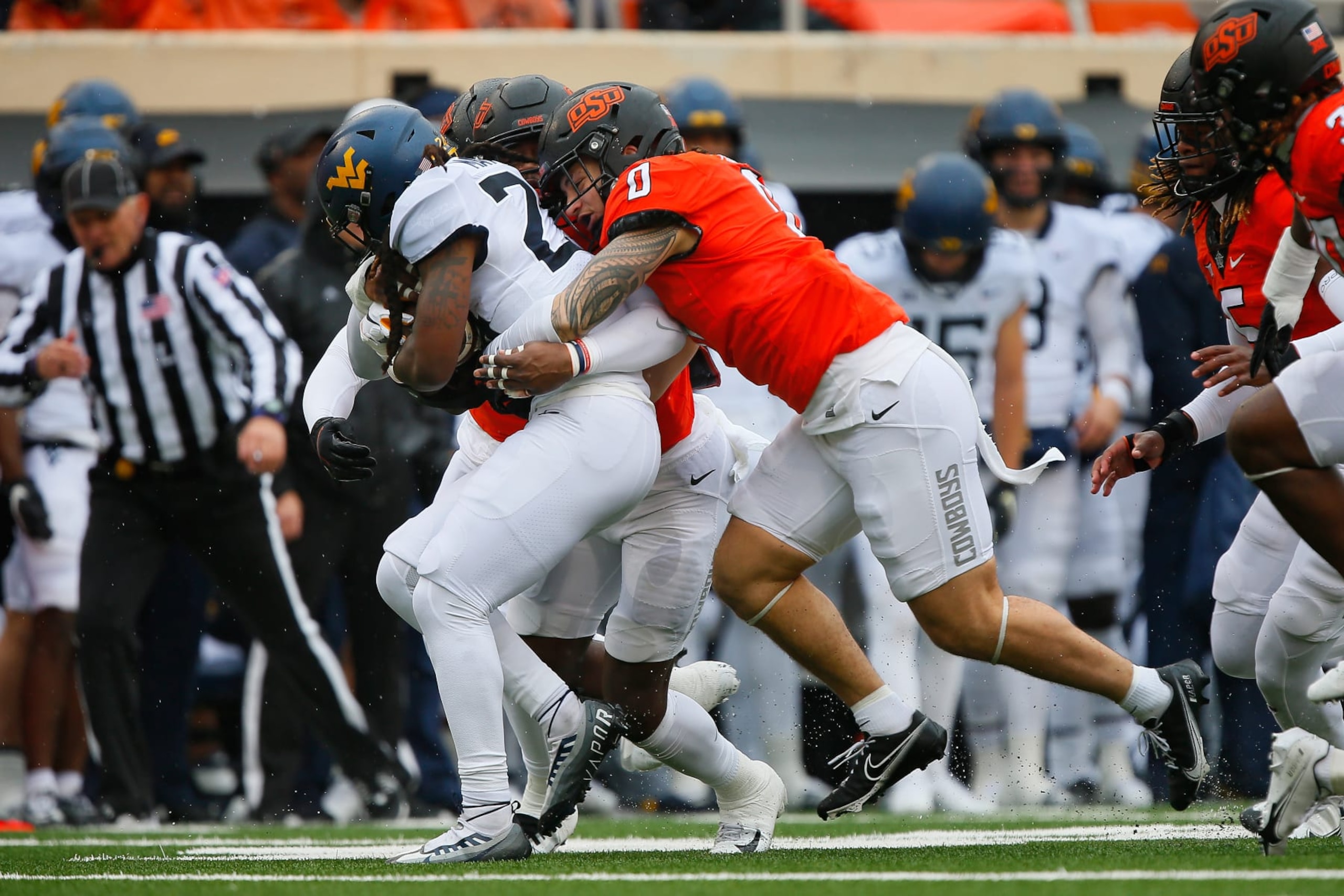 STILLWATER, OK - NOVEMBER 26:  Linebacker Mason Cobb #0 and linebacker Xavier Benson #1 of the Oklahoma State Cowboys stop running back Tony Mathis Jr. #24 of the West Virginia Mountaineers with a one yard loss in the first quarter at Boone Pickens Stadium on November 26, 2022 in Stillwater, Oklahoma.  West Virginia won 24-19.  (Photo by Brian Bahr/Getty Images)