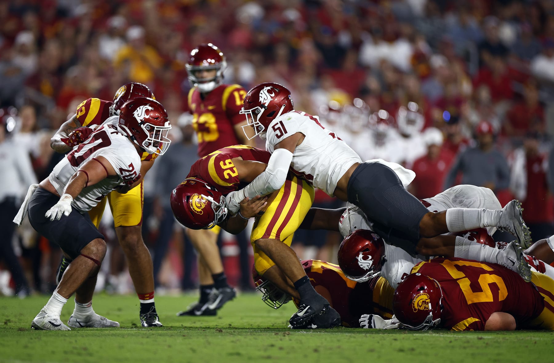 LOS ANGELES, CALIFORNIA - OCTOBER 08:   Travis Dye #26 of the USC Trojans is tackled by Francisco Mauigoa #51 of the Washington State Cougars in the third quarter at United Airlines Field at the Los Angeles Memorial Coliseum on October 08, 2022 in Los Angeles, California. (Photo by Ronald Martinez/Getty Images)