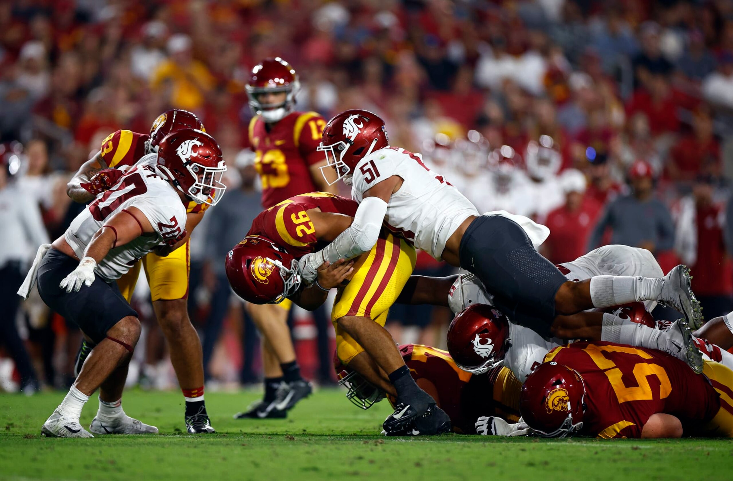 LOS ANGELES, CALIFORNIA - OCTOBER 08:   Travis Dye #26 of the USC Trojans is tackled by Francisco Mauigoa #51 of the Washington State Cougars in the third quarter at United Airlines Field at the Los Angeles Memorial Coliseum on October 08, 2022 in Los Angeles, California. (Photo by Ronald Martinez/Getty Images)