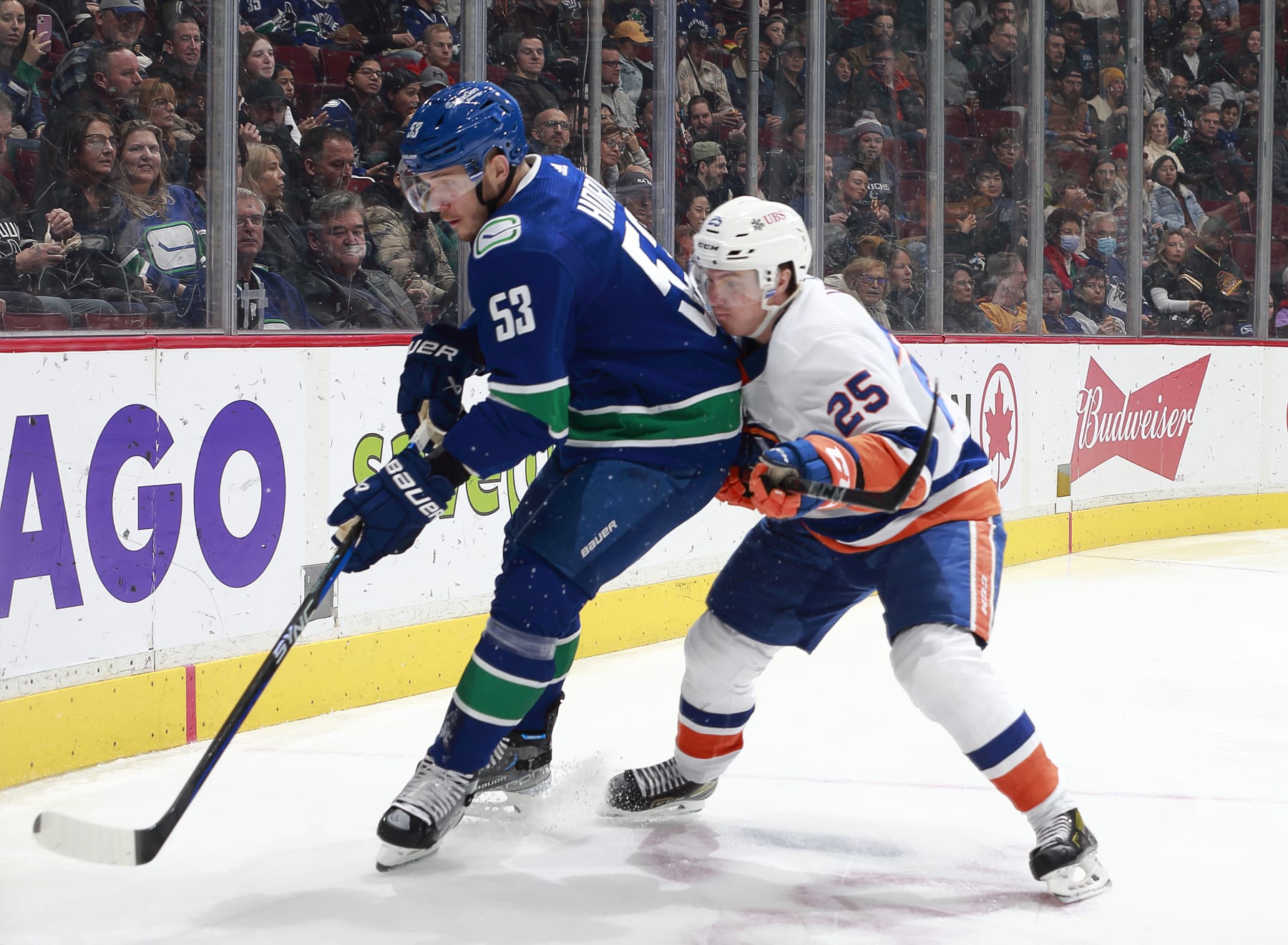 VANCOUVER, CANADA - JANUARY 3: Bo Horvat #53 of the Vancouver Canucks and Sebastian Aho #25 of the New York Islanders battle for the puck during the first period of their NHL game at Rogers Arena January 3, 2023 in Vancouver, British Columbia, Canada.  (Photo by Jeff Vinnick/NHLI via Getty Images)
