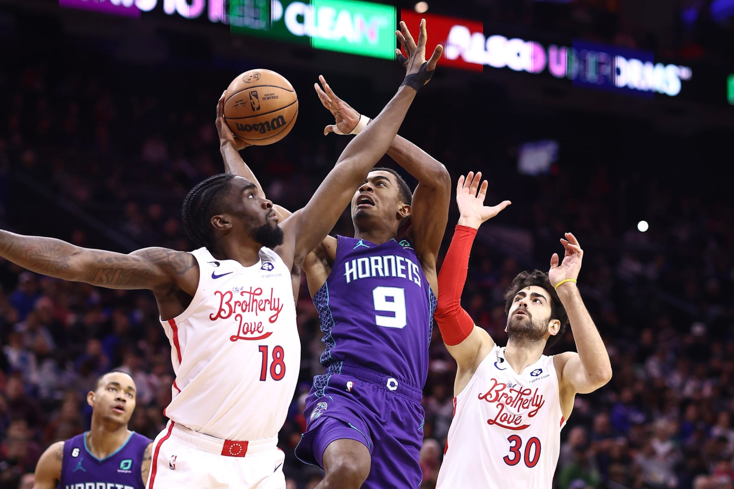 PHILADELPHIA, PENNSYLVANIA - DECEMBER 11: Theo Maledon #9 of the Charlotte Hornets shoots between Shake Milton #18 and Furkan Korkmaz #30 of the Philadelphia 76ers during the third quarter at Wells Fargo Center on December 11, 2022 in Philadelphia, Pennsylvania. NOTE TO USER: User expressly acknowledges and agrees that, by downloading and or using this photograph, User is consenting to the terms and conditions of the Getty Images License Agreement. (Photo by Tim Nwachukwu/Getty Images)