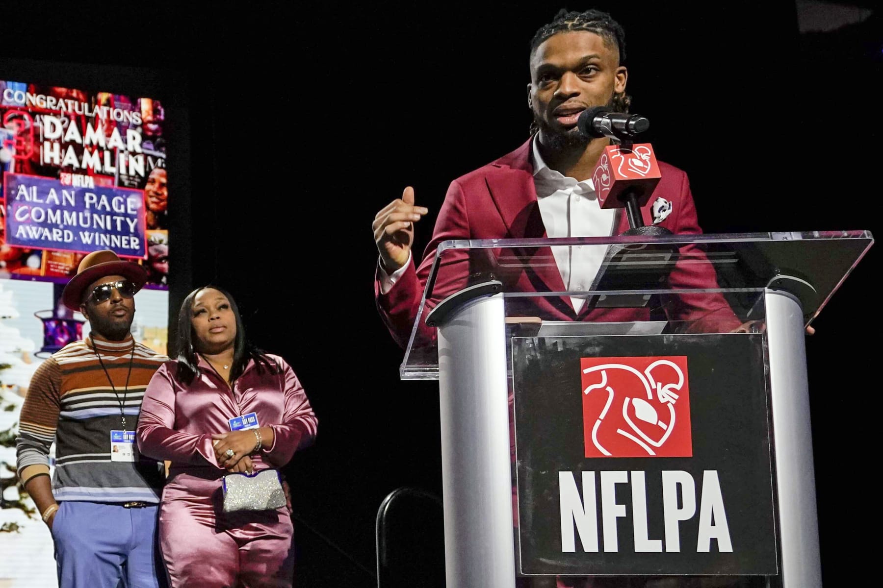 Buffalo Bills' Damar Hamlin, right, speaks after being introduced as the winner of the Alan Page Community Award during a news conference ahead of the Super Bowl 57 NFL football game, Wednesday, Feb. 8, 2023, in Phoenix. At left looking on are Damar Hamlin's parents Mario and Nina Hamlin. (AP Photo/Mike Stewart)