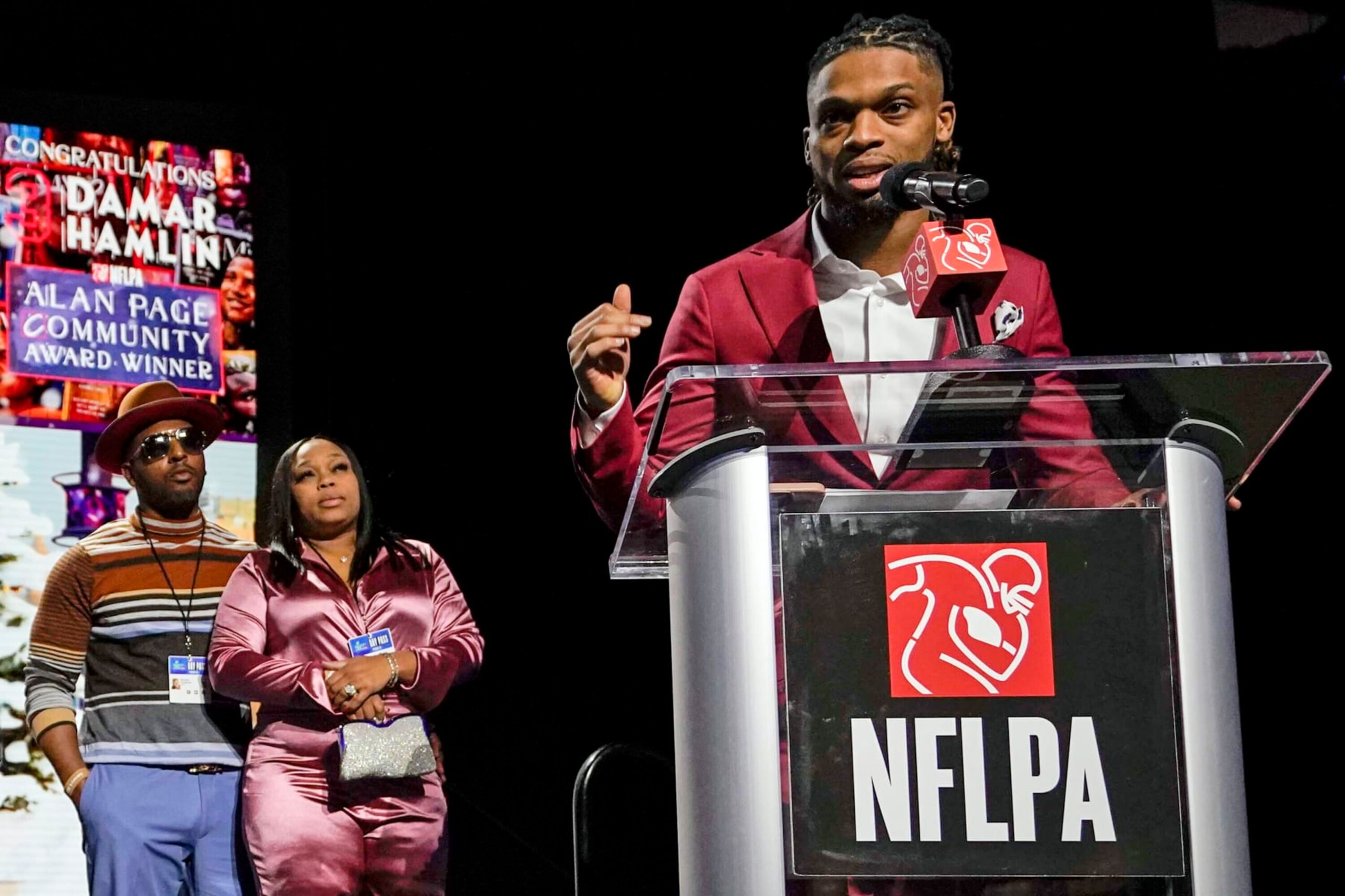 Buffalo Bills' Damar Hamlin, right, speaks after being introduced as the winner of the Alan Page Community Award during a news conference ahead of the Super Bowl 57 NFL football game, Wednesday, Feb. 8, 2023, in Phoenix. At left looking on are Damar Hamlin's parents Mario and Nina Hamlin. (AP Photo/Mike Stewart)