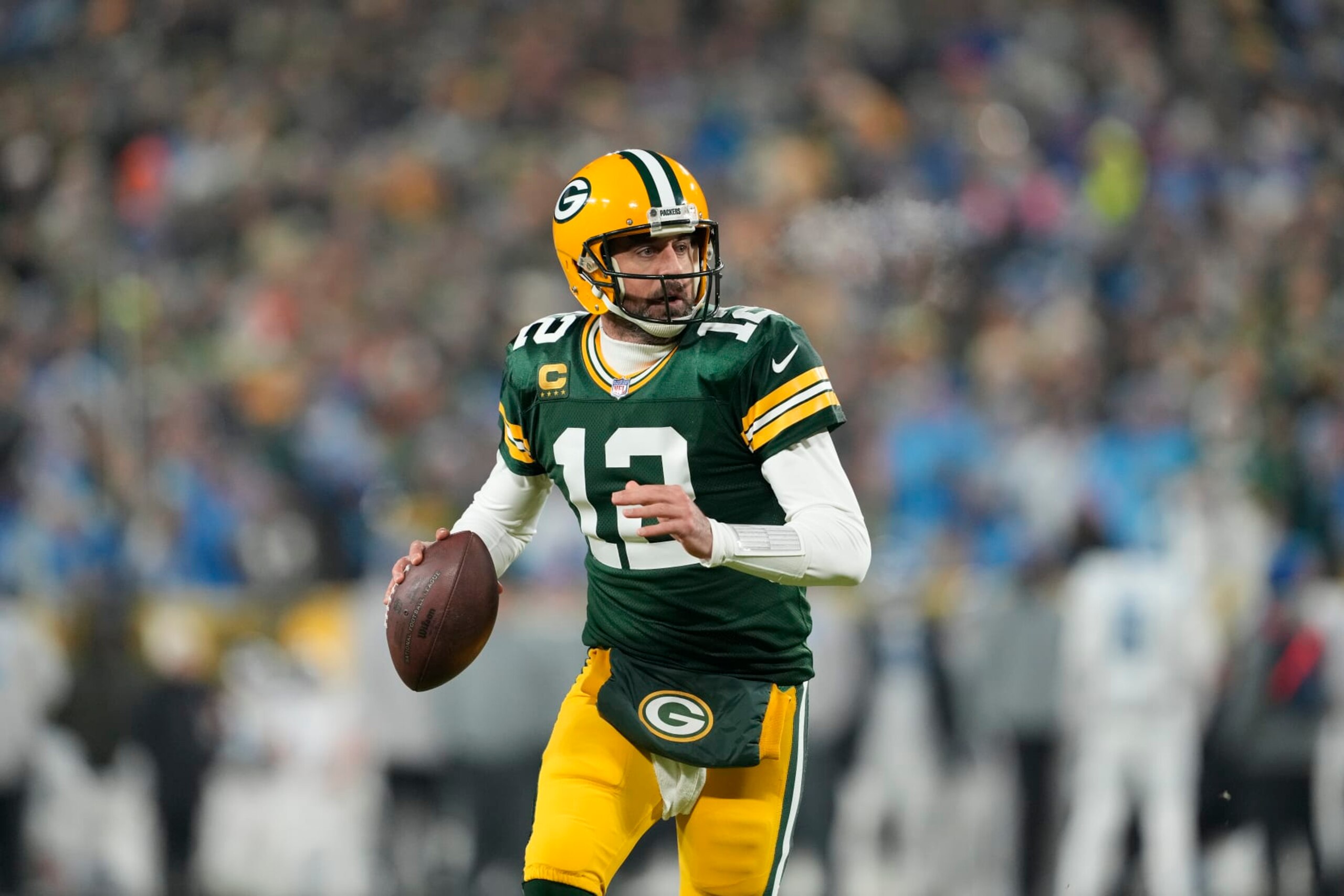 GREEN BAY, WISCONSIN - JANUARY 08: Aaron Rodgers #12 of the Green Bay Packers scrambles with the ball against the Detroit Lions in the first half at Lambeau Field on January 08, 2023 in Green Bay, Wisconsin. (Photo by Patrick McDermott/Getty Images)