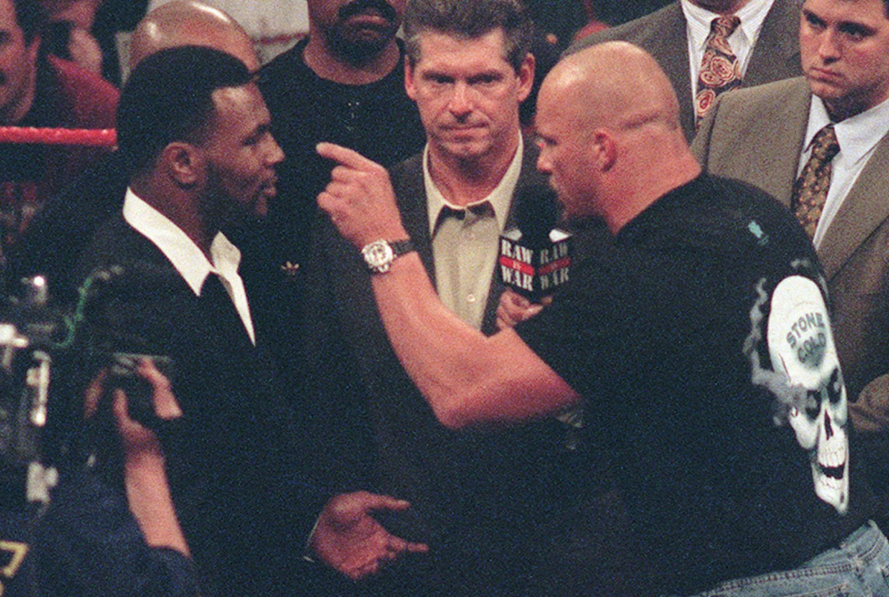 Stone Cold Steve Austin, right, points a finger and challenges Mike Tyson, left, to a professional wrestling match as Vince McMahon, center, CEO of the World Wrestling Federation listens in at WWF's Raw is War show on Monday, Jan. 19, 1998, in Fresno, Calif. Tyson had appeared as a guest of McMahon's and was about to announce Tyson's role as a guest referee for Wrestlemania XIV, an upcoming WWF event in Boston this March, when Stone Cold Steve Austin joined the group in the ring for the unexpected challenge. (AP Photo/Eric Paul Zamora)