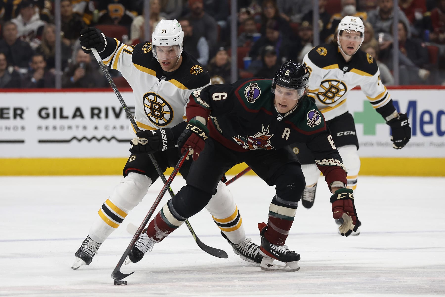GLENDALE, ARIZONA - JANUARY 28: Jakob Chychrun #6 of the Arizona Coyotes and Taylor Hall #71 of the Boston Bruins fight for control of the puck in the second period of the game  at Gila River Arena on January 28, 2022 in Glendale, Arizona. (Photo by Christian Petersen/Getty Images)