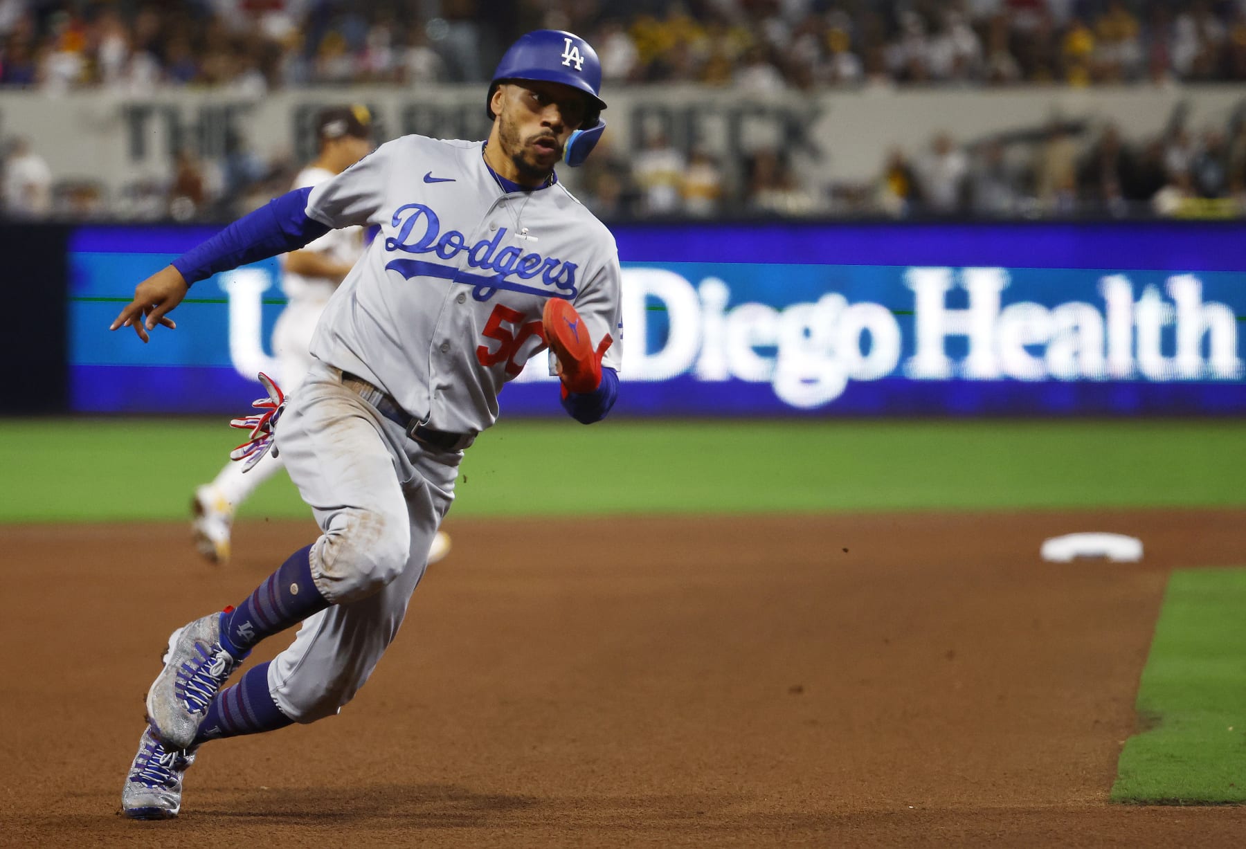 SAN DIEGO, CALIFORNIA - OCTOBER 15: Mookie Betts #50 of the Los Angeles Dodgers rounds third base on his way to scoring a run on a sacrifice fly ball hit by Will Smith #16 during the seventh inning against the San Diego Padres in game four of the National League Division Series at PETCO Park on October 15, 2022 in San Diego, California. (Photo by Ronald Martinez/Getty Images)