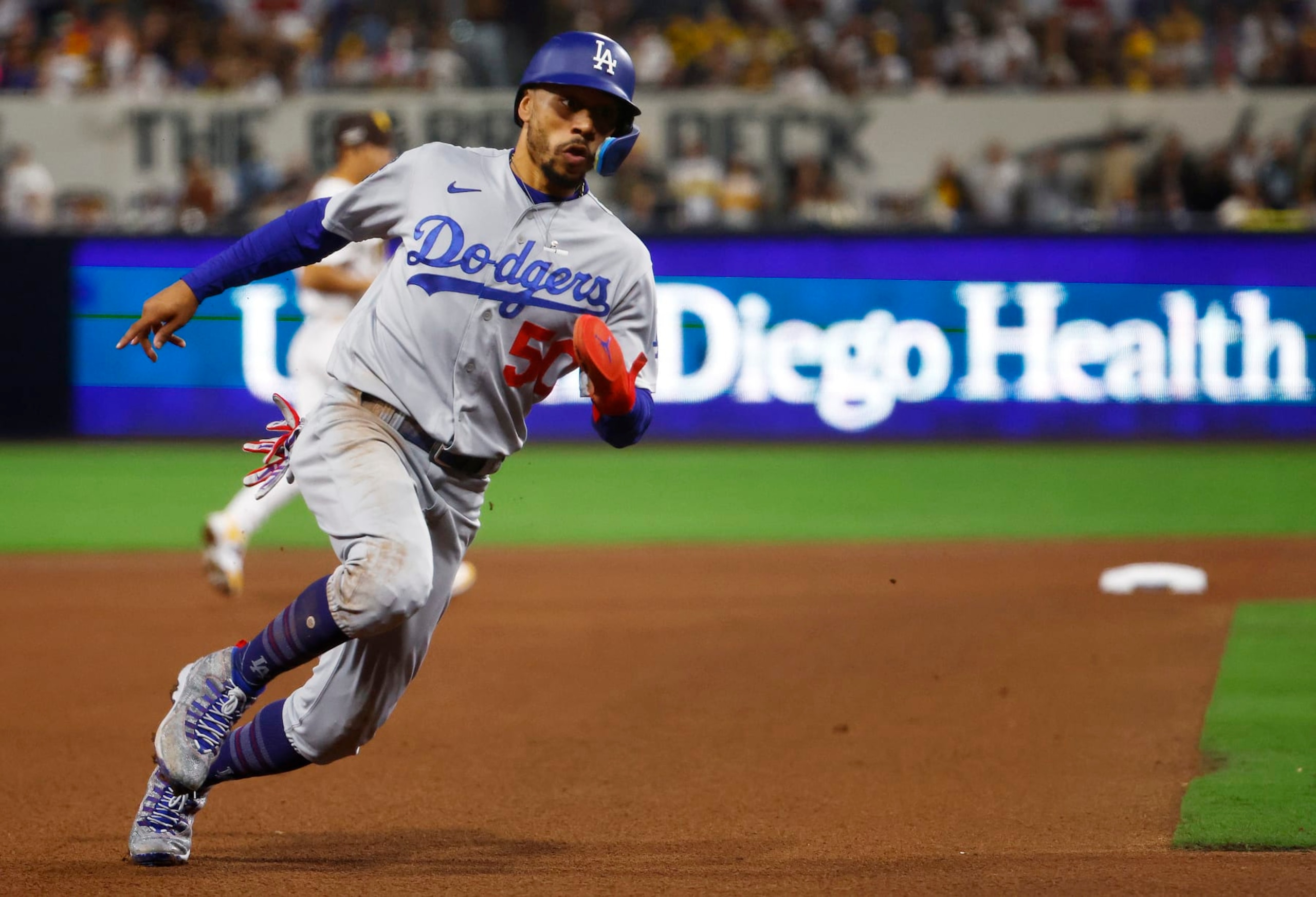 SAN DIEGO, CALIFORNIA - OCTOBER 15: Mookie Betts #50 of the Los Angeles Dodgers rounds third base on his way to scoring a run on a sacrifice fly ball hit by Will Smith #16 during the seventh inning against the San Diego Padres in game four of the National League Division Series at PETCO Park on October 15, 2022 in San Diego, California. (Photo by Ronald Martinez/Getty Images)