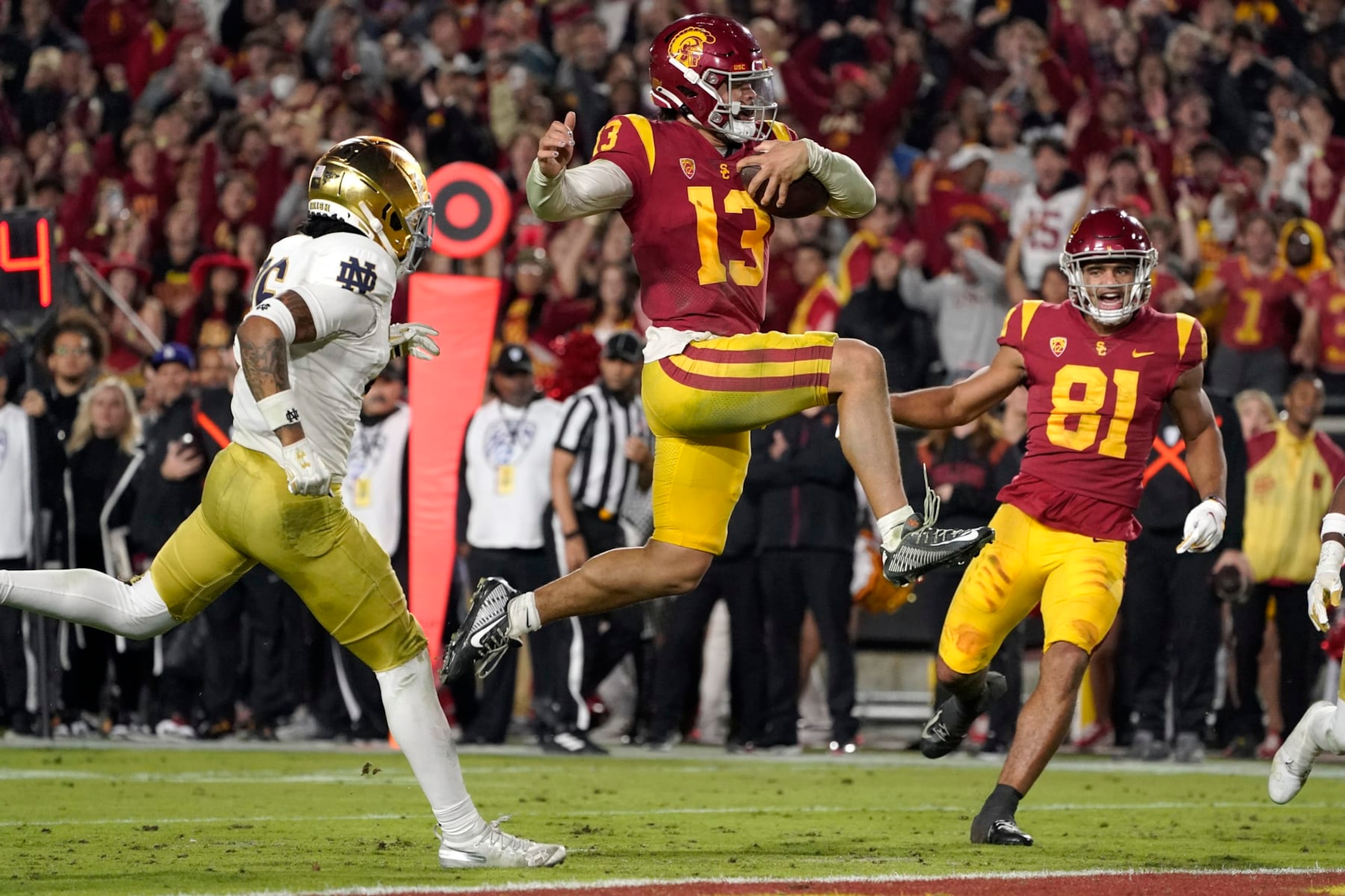 CORRECTS TO SECOND HALF, INSTEAD OF FIRST - Southern California quarterback Caleb Williams jumps in for a touchdown as Notre Dame safety Xavier Watts, left, defends and Southern California wide receiver Kyle Ford watches during the second half of an NCAA college football game Saturday, Nov. 26, 2022, in Los Angeles. (AP Photo/Mark J. Terrill)