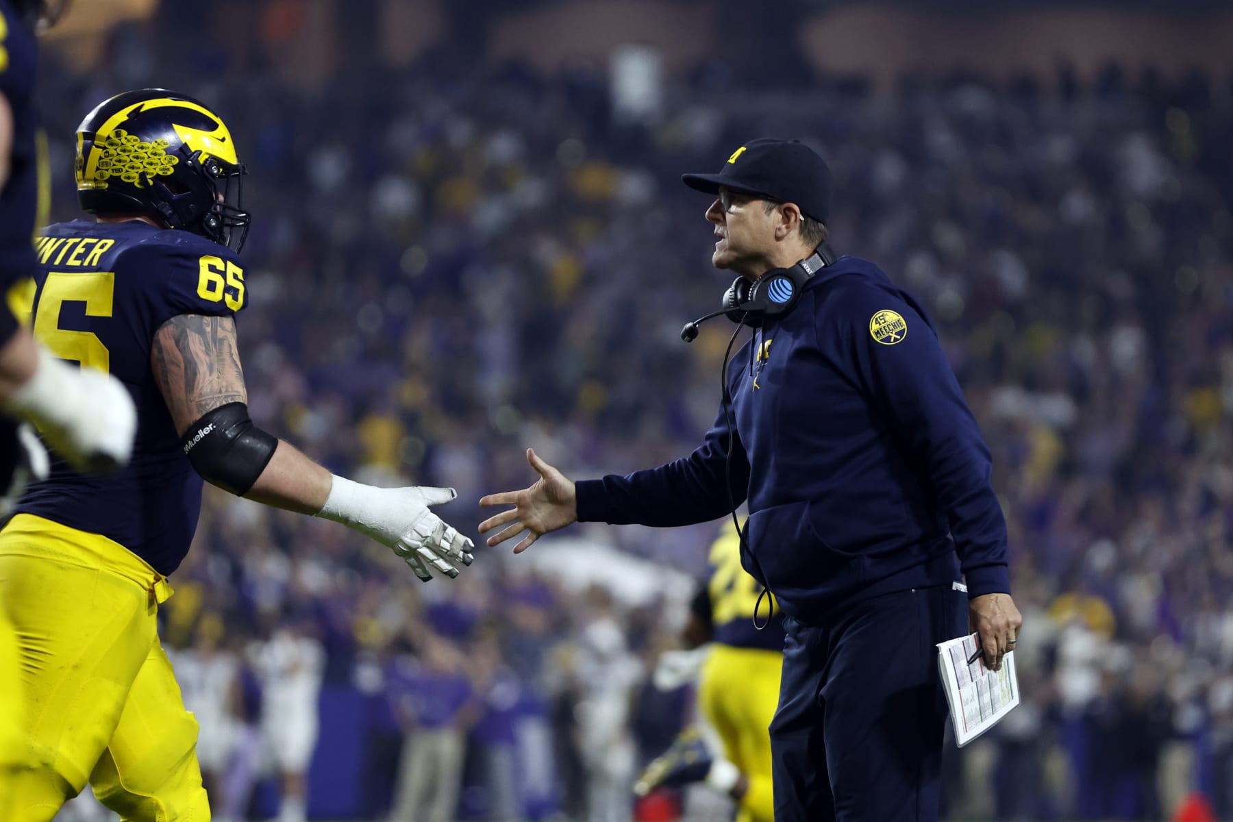 GLENDALE, ARIZONA - DECEMBER 31: Head coach Jim Harbaugh shakes hands with offensive lineman Zak Zinter #65 of the Michigan Wolverines during the second half of the Vrbo Fiesta Bowl against the TCU Horned Frogs at State Farm Stadium on December 31, 2022 in Glendale, Arizona. The Horned Frogs defeated the Wolverines 51-45. (Photo by Chris Coduto/Getty Images)