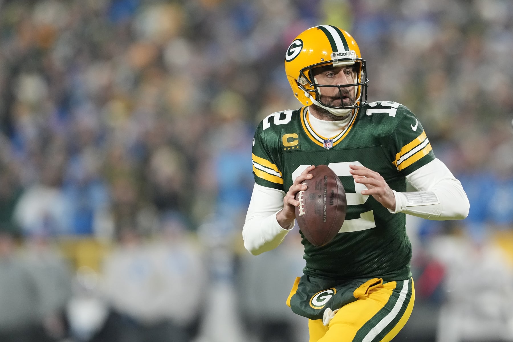GREEN BAY, WISCONSIN - JANUARY 08: Aaron Rodgers #12 of the Green Bay Packers scrambles with the ball against the Detroit Lions in the first half at Lambeau Field on January 08, 2023 in Green Bay, Wisconsin. (Photo by Patrick McDermott/Getty Images)