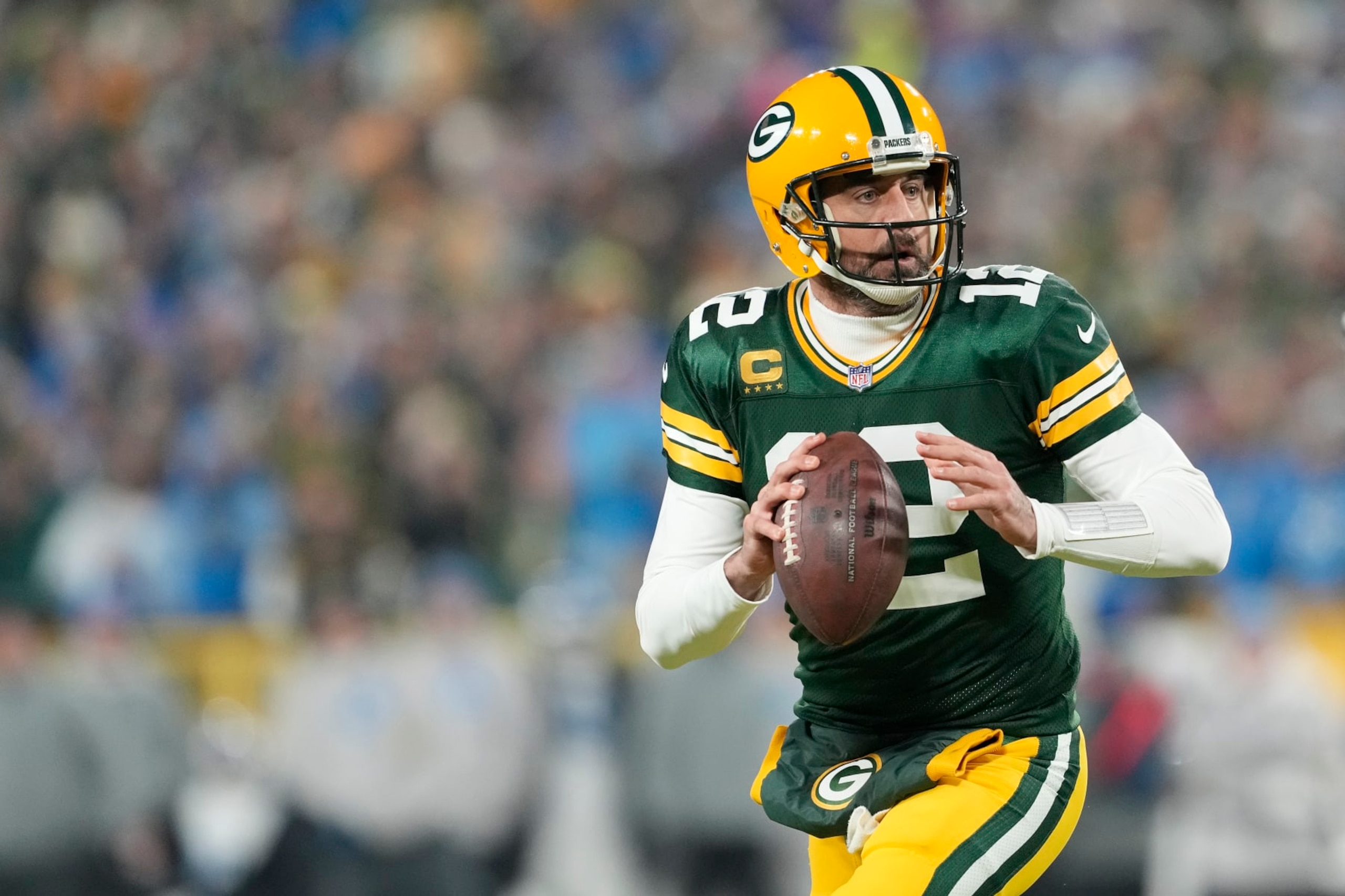 GREEN BAY, WISCONSIN - JANUARY 08: Aaron Rodgers #12 of the Green Bay Packers scrambles with the ball against the Detroit Lions in the first half at Lambeau Field on January 08, 2023 in Green Bay, Wisconsin. (Photo by Patrick McDermott/Getty Images)