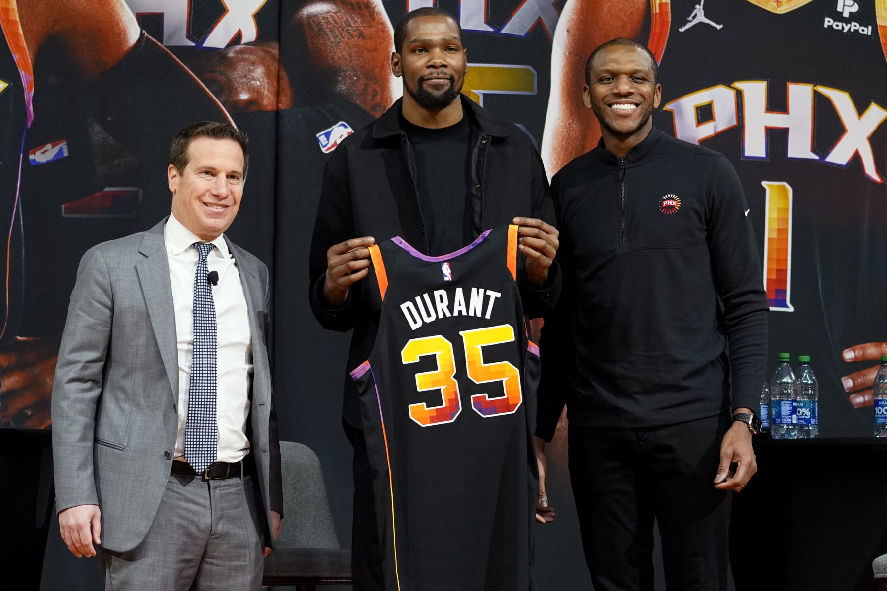 Phoenix Suns forward Kevin Durant, center, holds his jersey after being introduced during an NBA basketball team availability by owner Mat Ishbia, left, and general manager James Jones, Thursday, Feb. 16, 2023, in Phoenix. (AP Photo/Matt York)