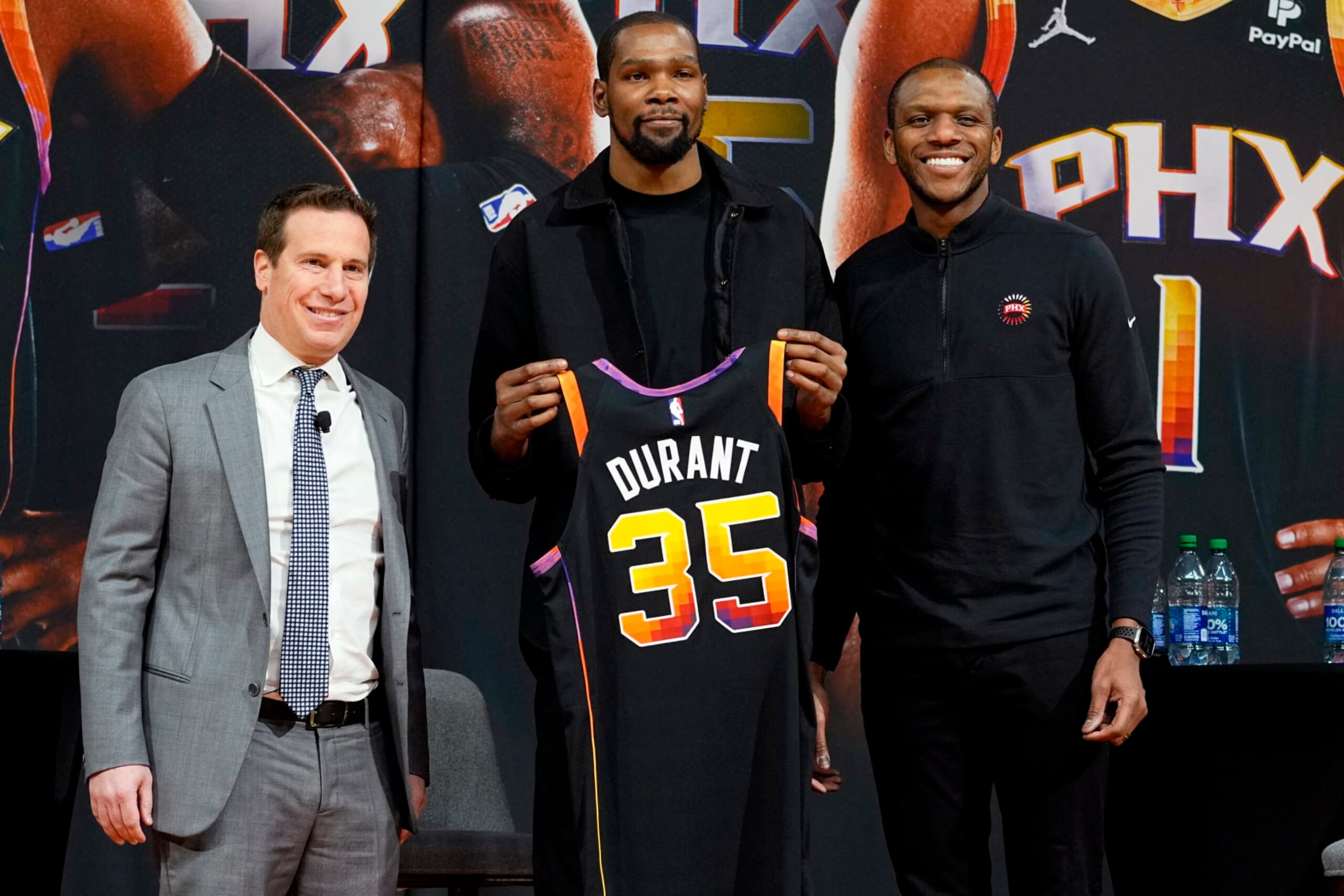 Phoenix Suns forward Kevin Durant, center, holds his jersey after being introduced during an NBA basketball team availability by owner Mat Ishbia, left, and general manager James Jones, Thursday, Feb. 16, 2023, in Phoenix. (AP Photo/Matt York)