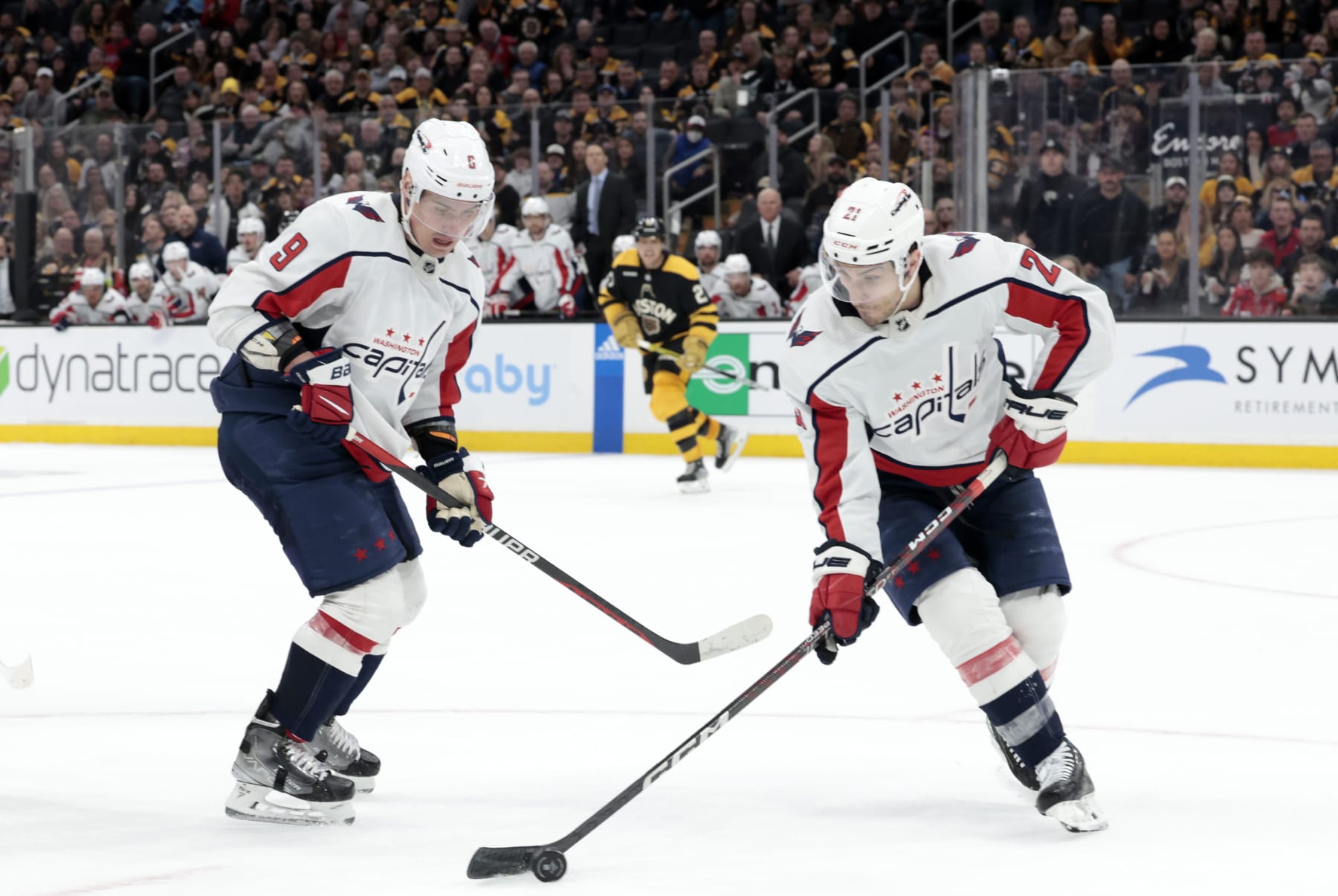 BOSTON, MA - FEBRUARY 11: Washington Capitals right wing Garnet Hathaway (21) grabs the puck watched by defenseman Dmitry Orlov (9) during a game between the Boston Bruins and the Washington Capitals on February 11, 2023, at TD Garden in Boston, Massachusetts. (Photo by Fred Kfoury III/Icon Sportswire via Getty Images)