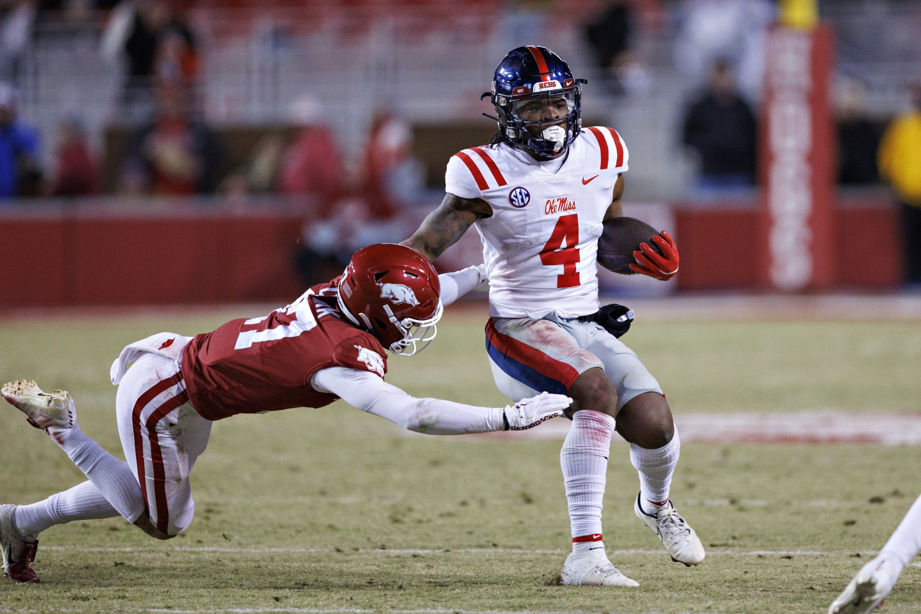 FAYETTEVILLE, ARKANSAS - NOVEMBER 19: Quinshon Judkins #4 of the Mississippi Rebels runs the ball in the second half as Hudson Clark #17 of the Arkansas Razorbacks goes for the tackle at Donald W. Reynolds Razorback Stadium on November 19, 2022 in Fayetteville, Arkansas. The Razorbacks defeated the Rebels 42-27.  (Photo by Wesley Hitt/Getty Images)
