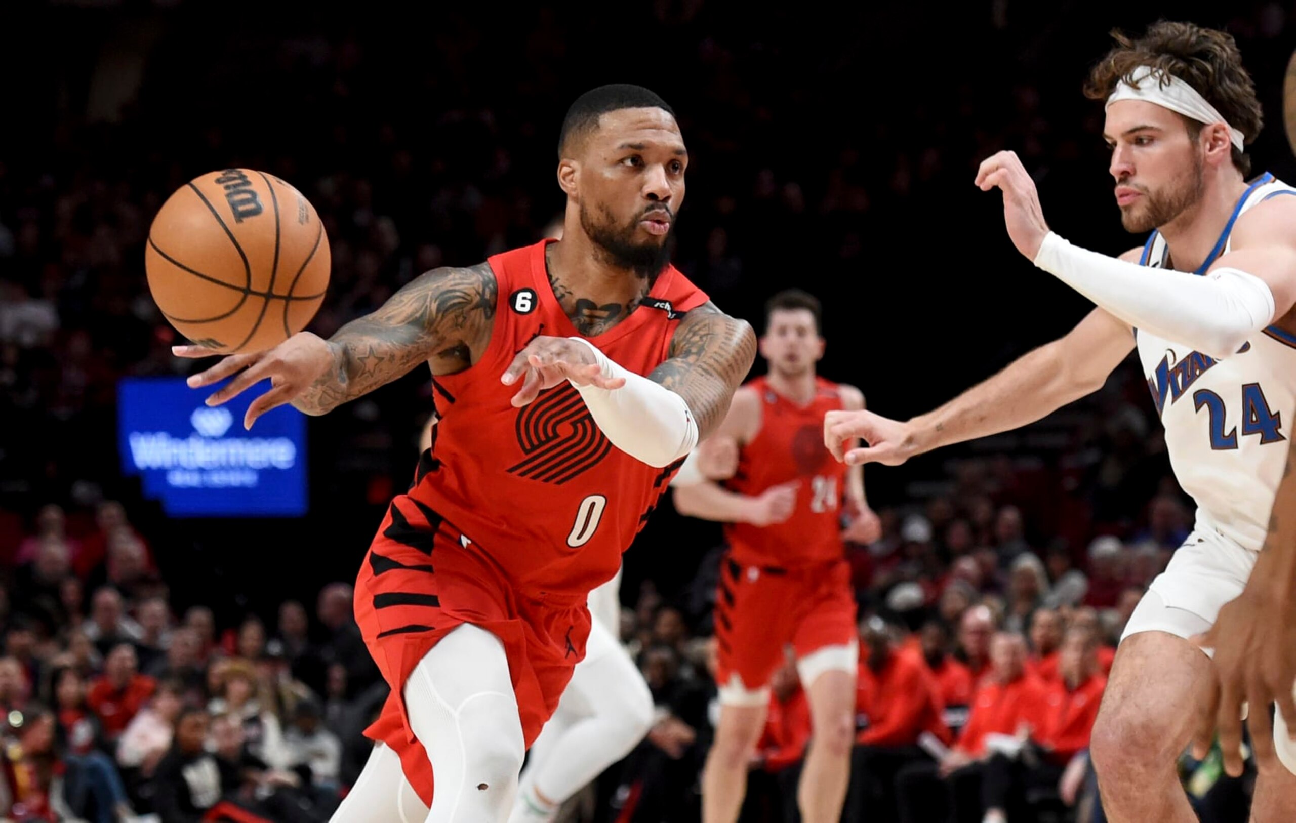 Portland Trail Blazers guard Damian Lillard, left, passes the ball as Washington Wizards forward Corey Kispert, right, defends during the first half of an NBA basketball game in Portland, Ore., Tuesday, Feb. 14, 2023. (AP Photo/Steve Dykes)