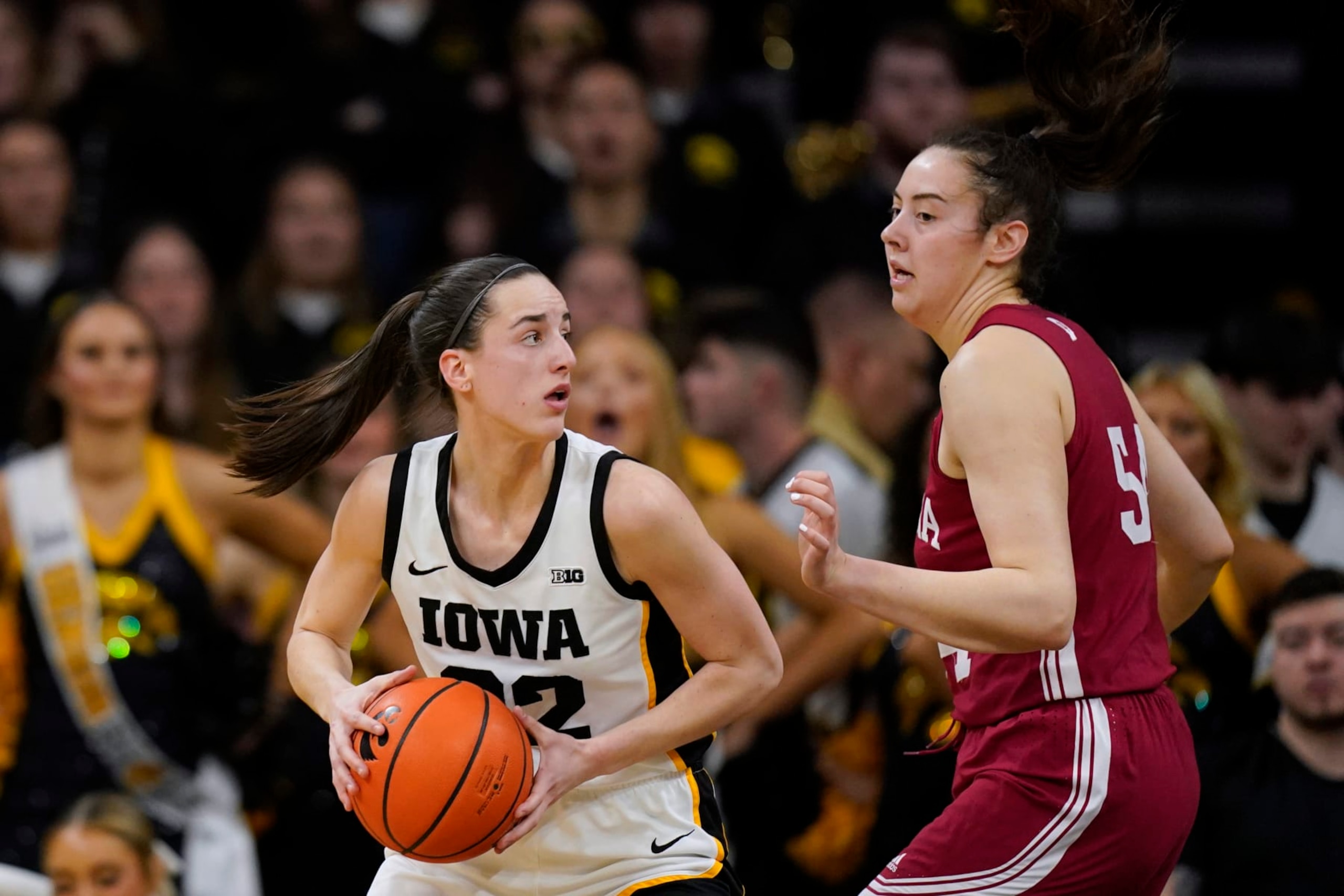 Iowa guard Caitlin Clark (22) drives around Indiana forward Mackenzie Holmes, right, during the first half of an NCAA college basketball game, Sunday, Feb. 26, 2023, in Iowa City, Iowa. (AP Photo/Charlie Neibergall)