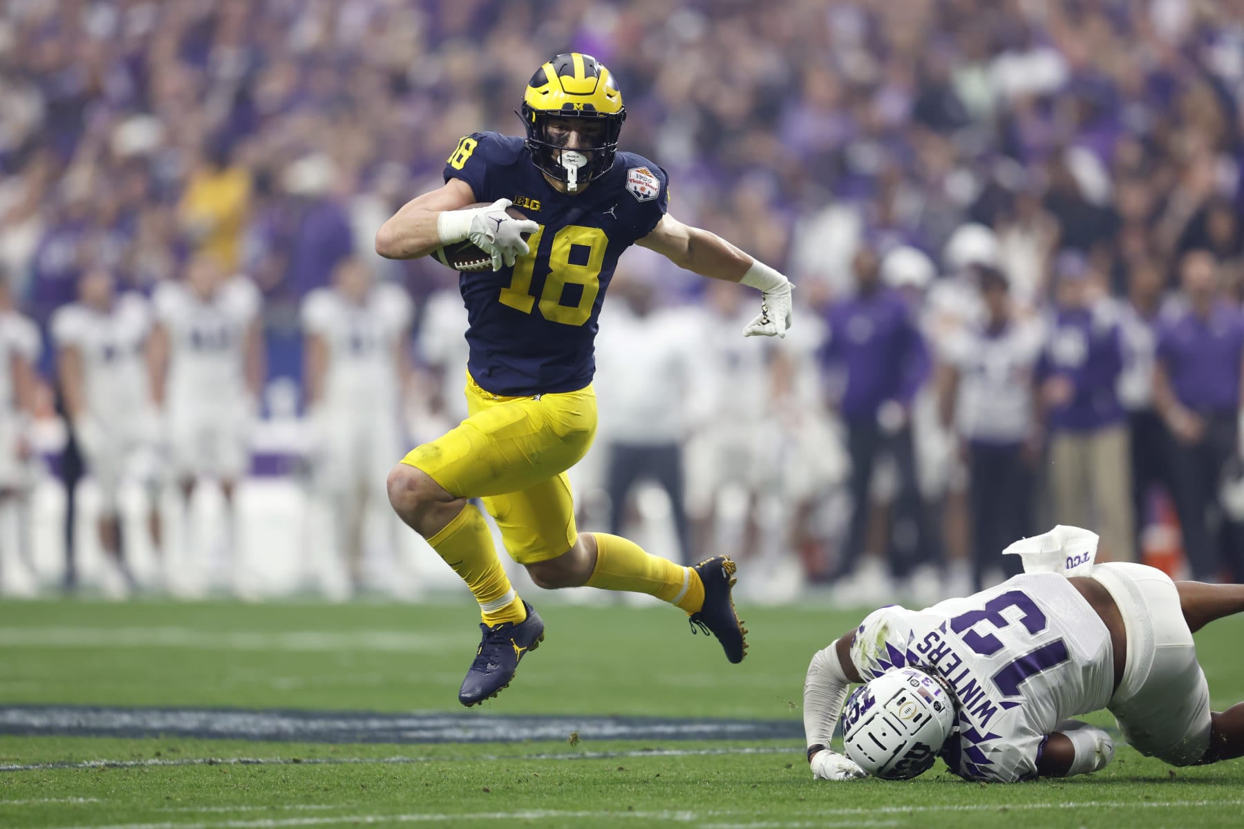 GLENDALE, ARIZONA - DECEMBER 31: Tight end Colston Loveland #18 of the Michigan Wolverines runs past linebacker Dee Winters #13 of the TCU Horned Frogs during the first half of the Vrbo Fiesta Bowl at State Farm Stadium on December 31, 2022 in Glendale, Arizona. The Horned Frogs defeated the Wolverines 51-45. (Photo by Chris Coduto/Getty Images)