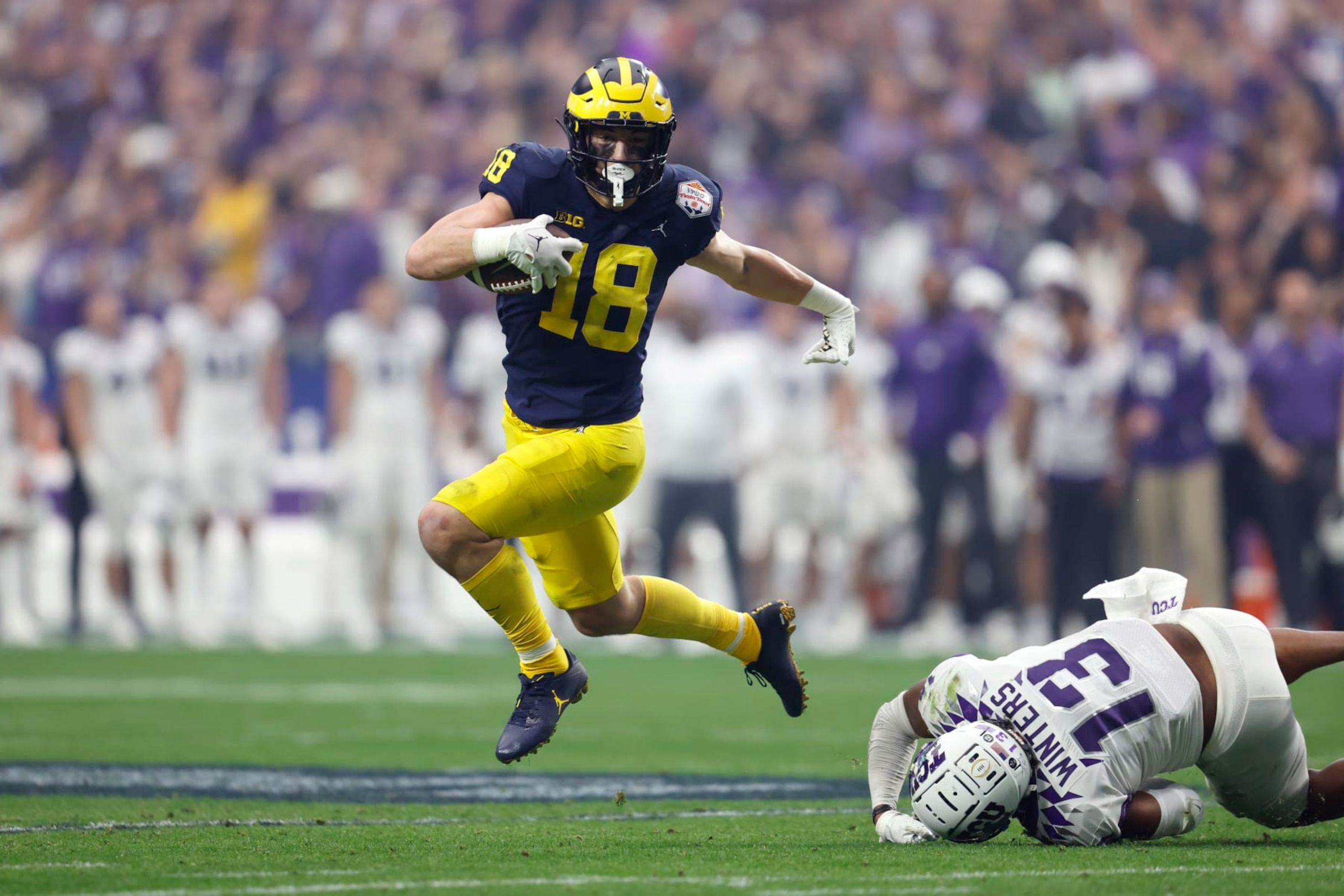 GLENDALE, ARIZONA - DECEMBER 31: Tight end Colston Loveland #18 of the Michigan Wolverines runs past linebacker Dee Winters #13 of the TCU Horned Frogs during the first half of the Vrbo Fiesta Bowl at State Farm Stadium on December 31, 2022 in Glendale, Arizona. The Horned Frogs defeated the Wolverines 51-45. (Photo by Chris Coduto/Getty Images)
