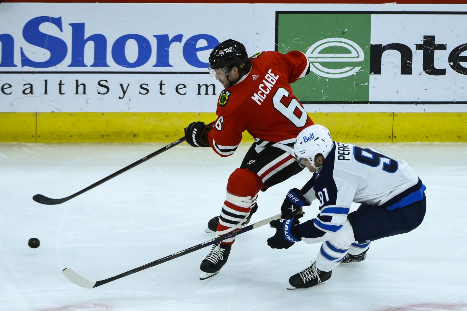 Chicago Blackhawks defenseman Jake McCabe (6) moves the puck away from Winnipeg Jets center Cole Perfetti (91) during the third period of an NHL hockey game, Sunday, Nov. 27, 2022, in Chicago. (AP Photo/Matt Marton)
