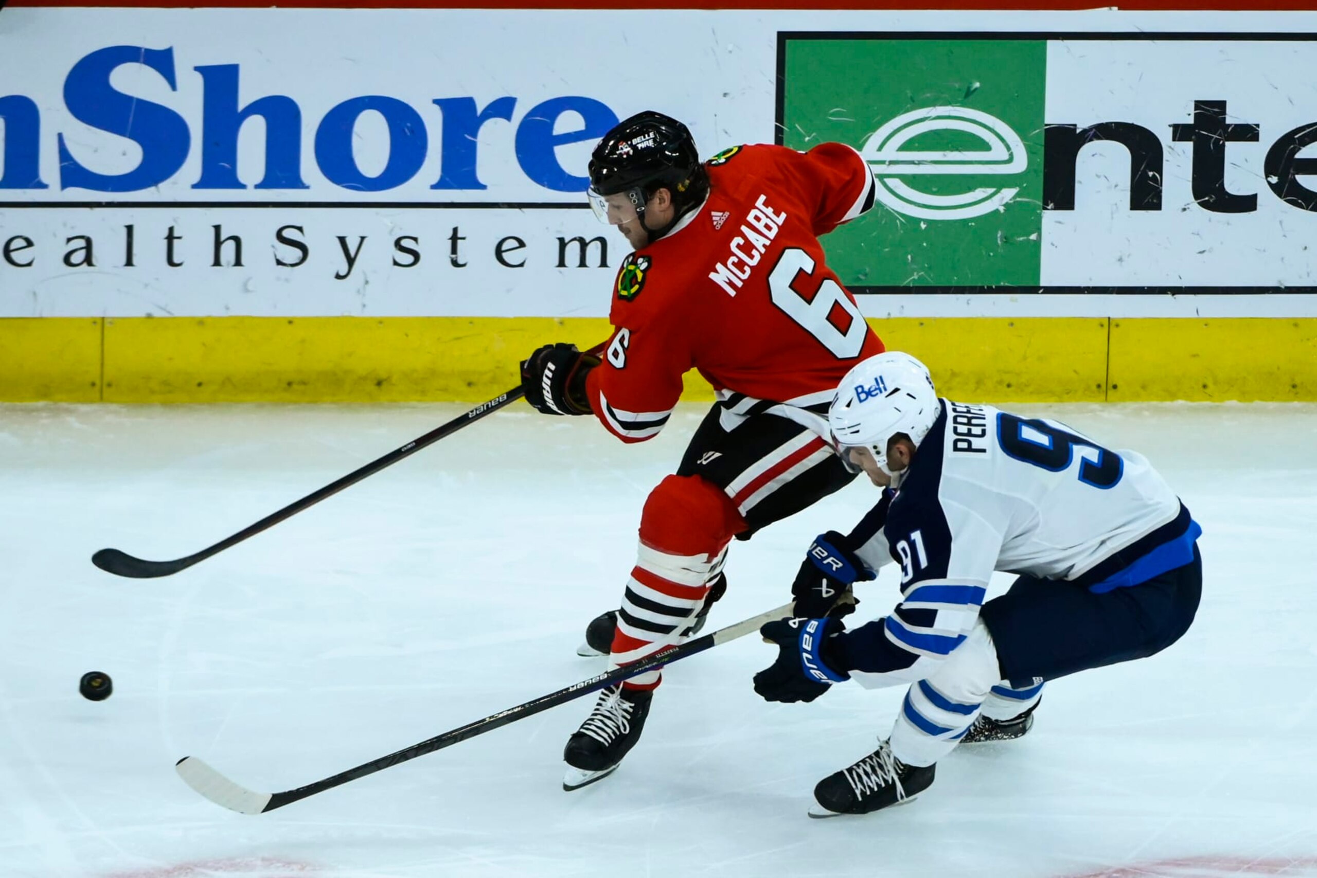 Chicago Blackhawks defenseman Jake McCabe (6) moves the puck away from Winnipeg Jets center Cole Perfetti (91) during the third period of an NHL hockey game, Sunday, Nov. 27, 2022, in Chicago. (AP Photo/Matt Marton)