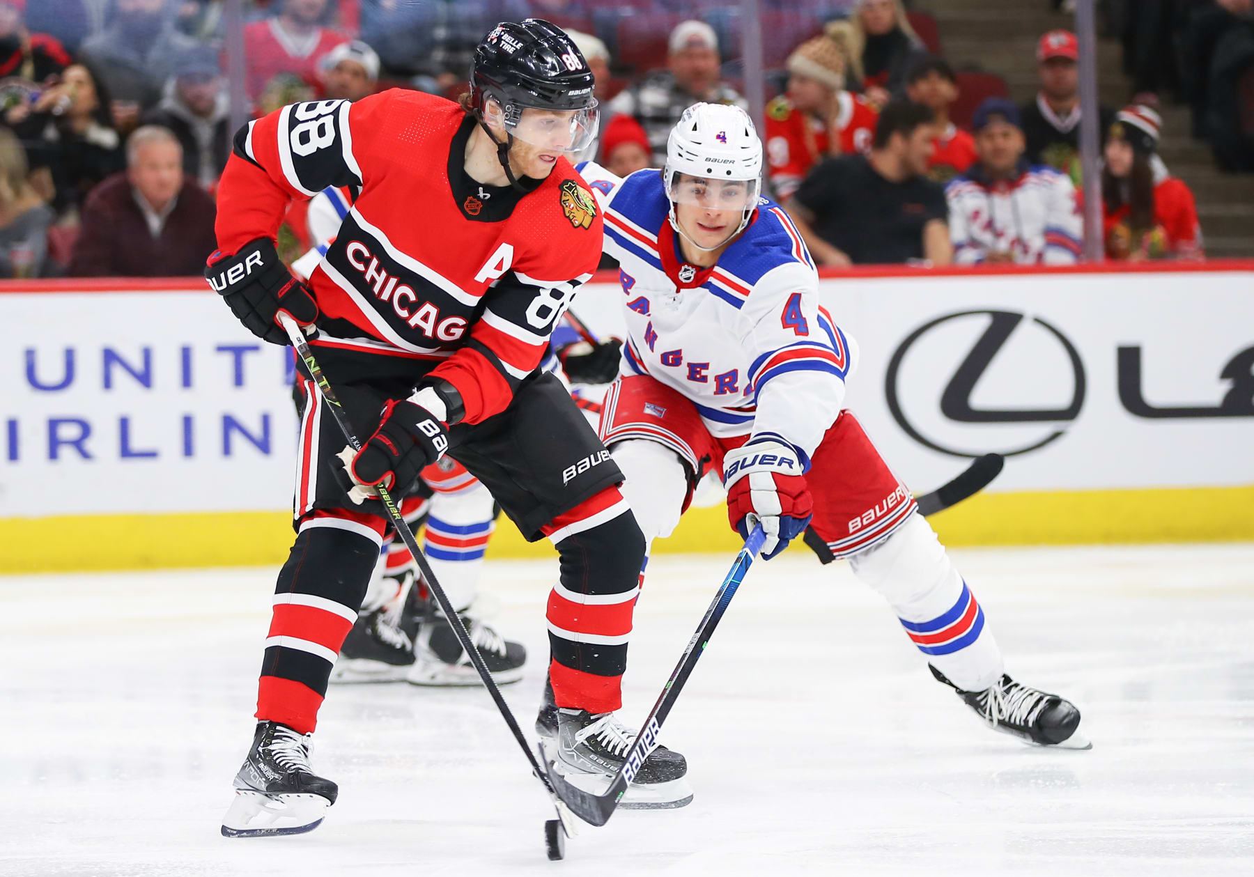 CHICAGO, IL - DECEMBER 18: New York Rangers Defenceman Braden Schneider (4) poke checks the puck away from Chicago Blackhawks Right Wing Patrick Kane (88) during a game between the New York Rangers and the Chicago Blackhawks on December 18, 2022 at the United Center in Chicago, IL. (Photo by Melissa Tamez/Icon Sportswire via Getty Images)