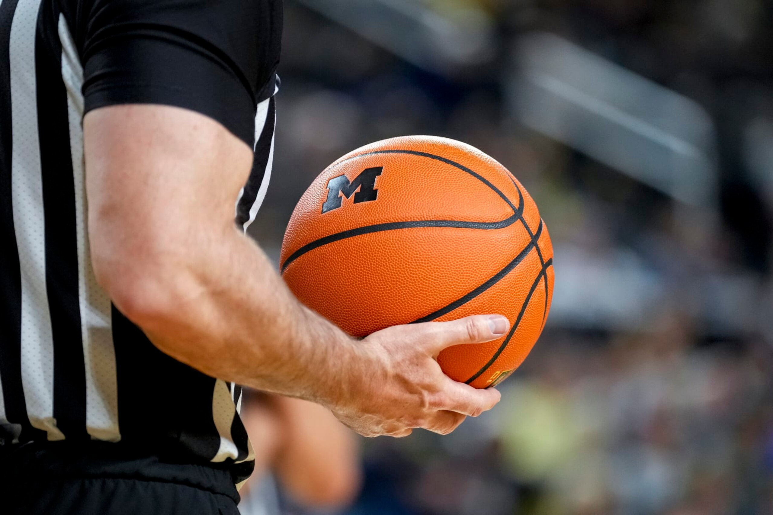 ANN ARBOR, MICHIGAN - FEBRUARY 26: A referee holds a basketball with the Michigan Wolverines logo during the game between the Wisconsin Badgers and Michigan Wolverines at Crisler Arena on February 26, 2023 in Ann Arbor, Michigan. (Photo by Nic Antaya/Getty Images)