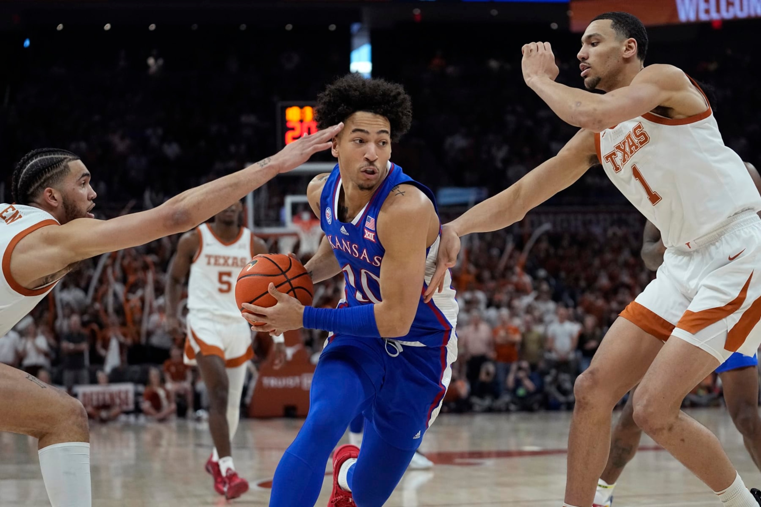 Kansas forward Jalen Wilson (10) drives between Texas forward Timmy Allen, left, and forward Dylan Disu (1) during the first half of an NCAA college basketball game in Austin, Texas, Saturday, March 4, 2023. (AP Photo/Eric Gay)