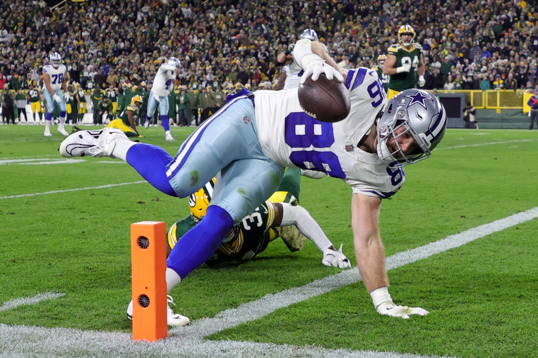 GREEN BAY, WISCONSIN - NOVEMBER 13: Dalton Schultz #86 of the Dallas Cowboys dives past Adrian Amos #31 of the Green Bay Packers while scoring a touchdown during the second quarter at Lambeau Field on November 13, 2022 in Green Bay, Wisconsin. (Photo by Stacy Revere/Getty Images)
